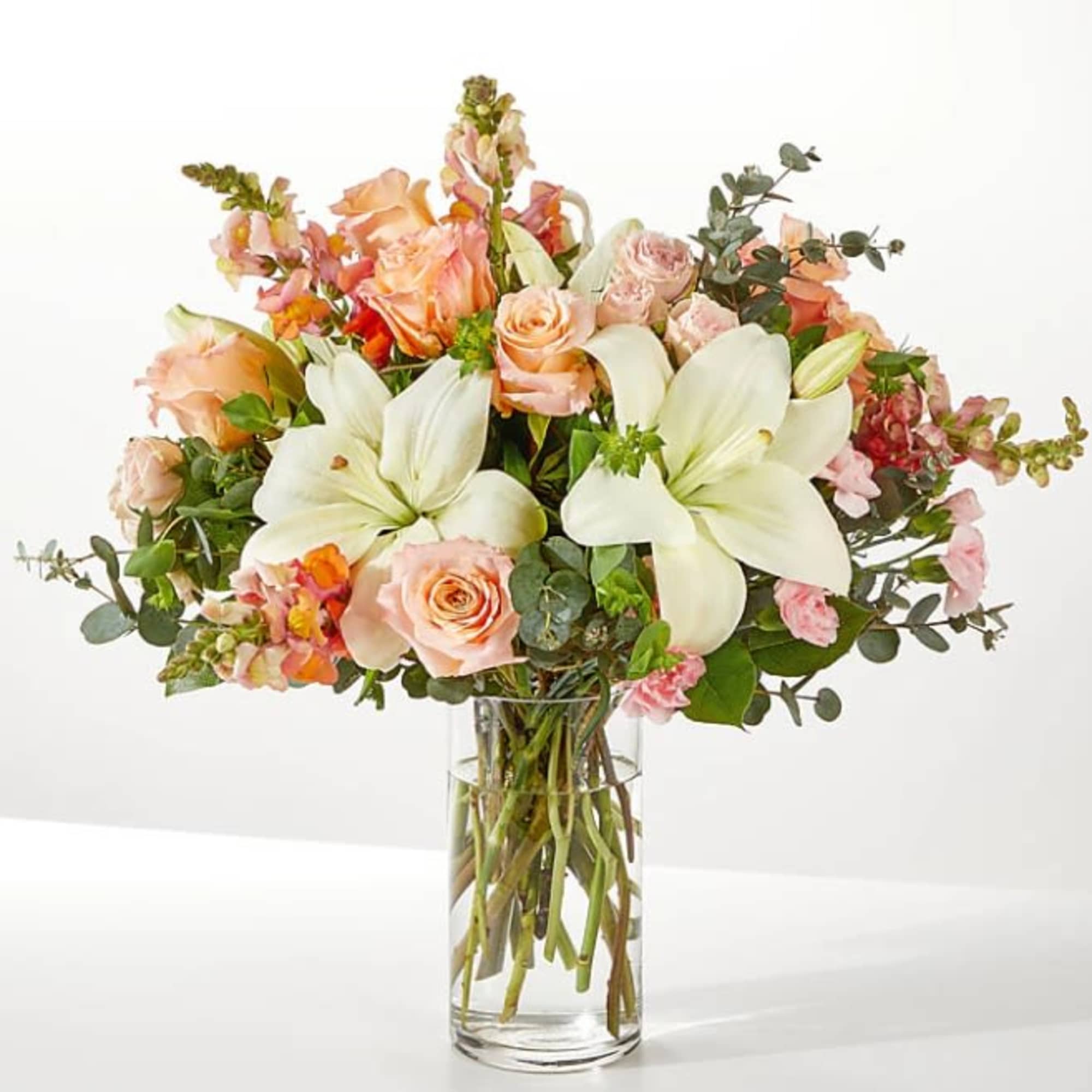 Bouquet of peach roses and white lilies in a clear glass vase