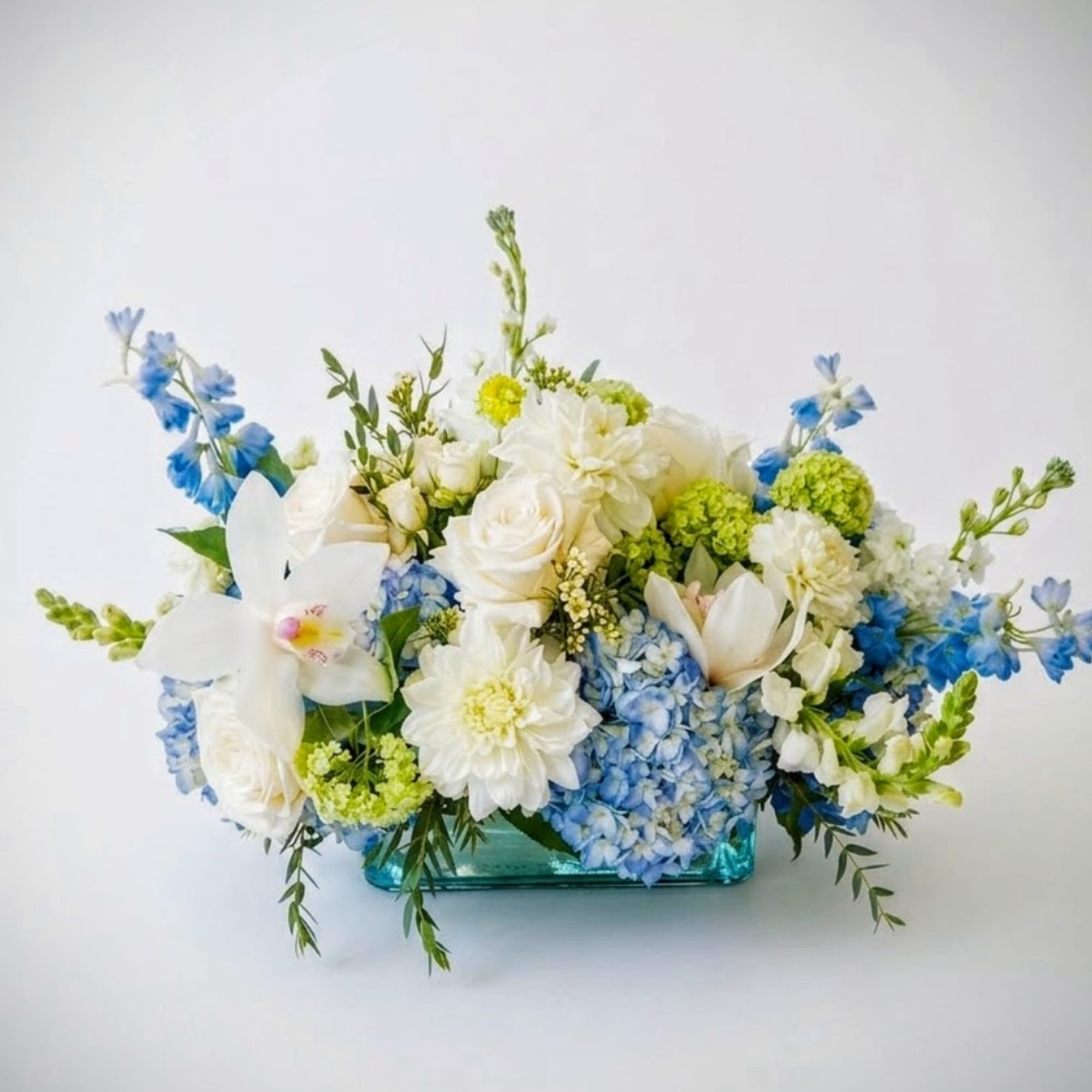 Blue and white floral arrangement in a turquoise glass vase