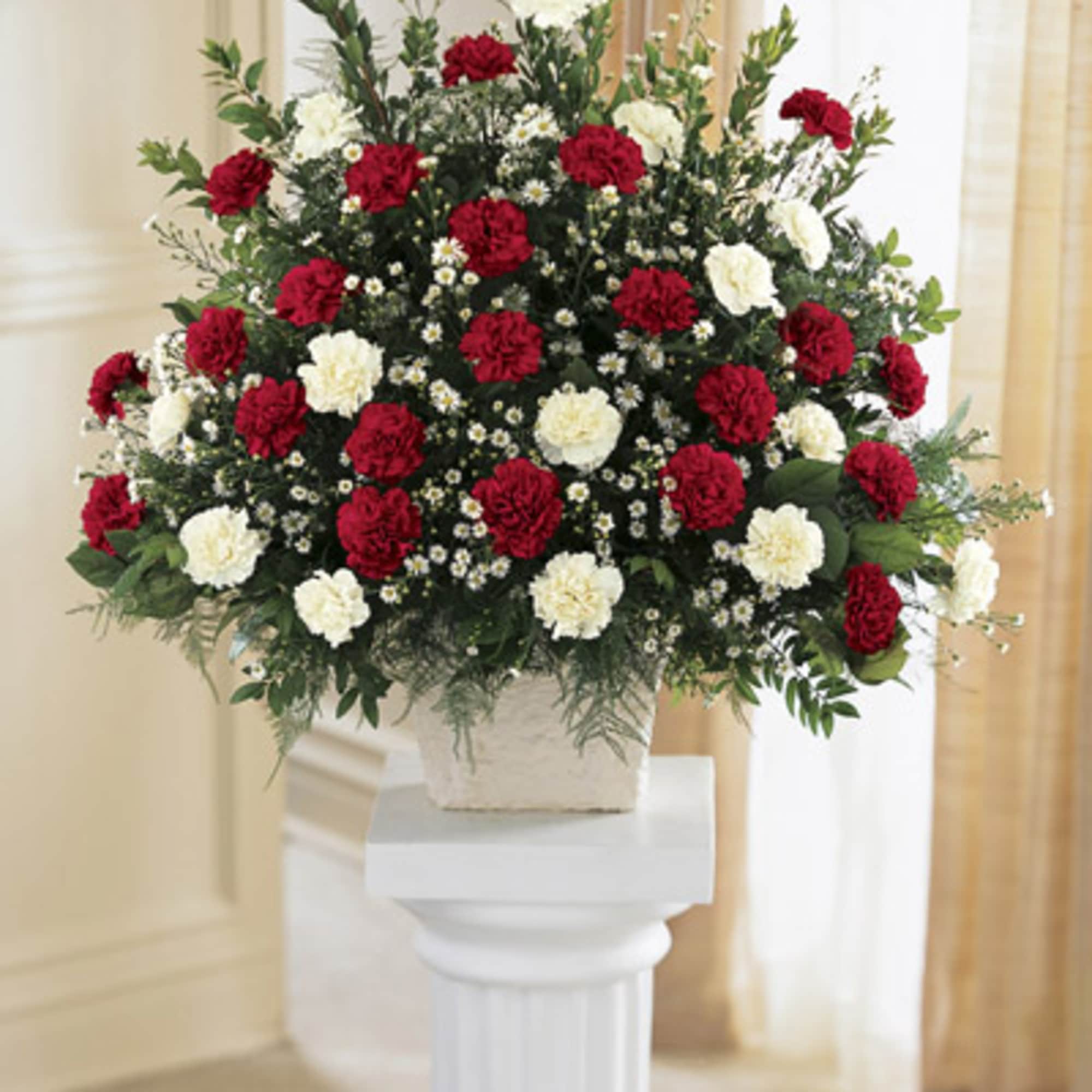 Large red and white carnation arrangement in a square container