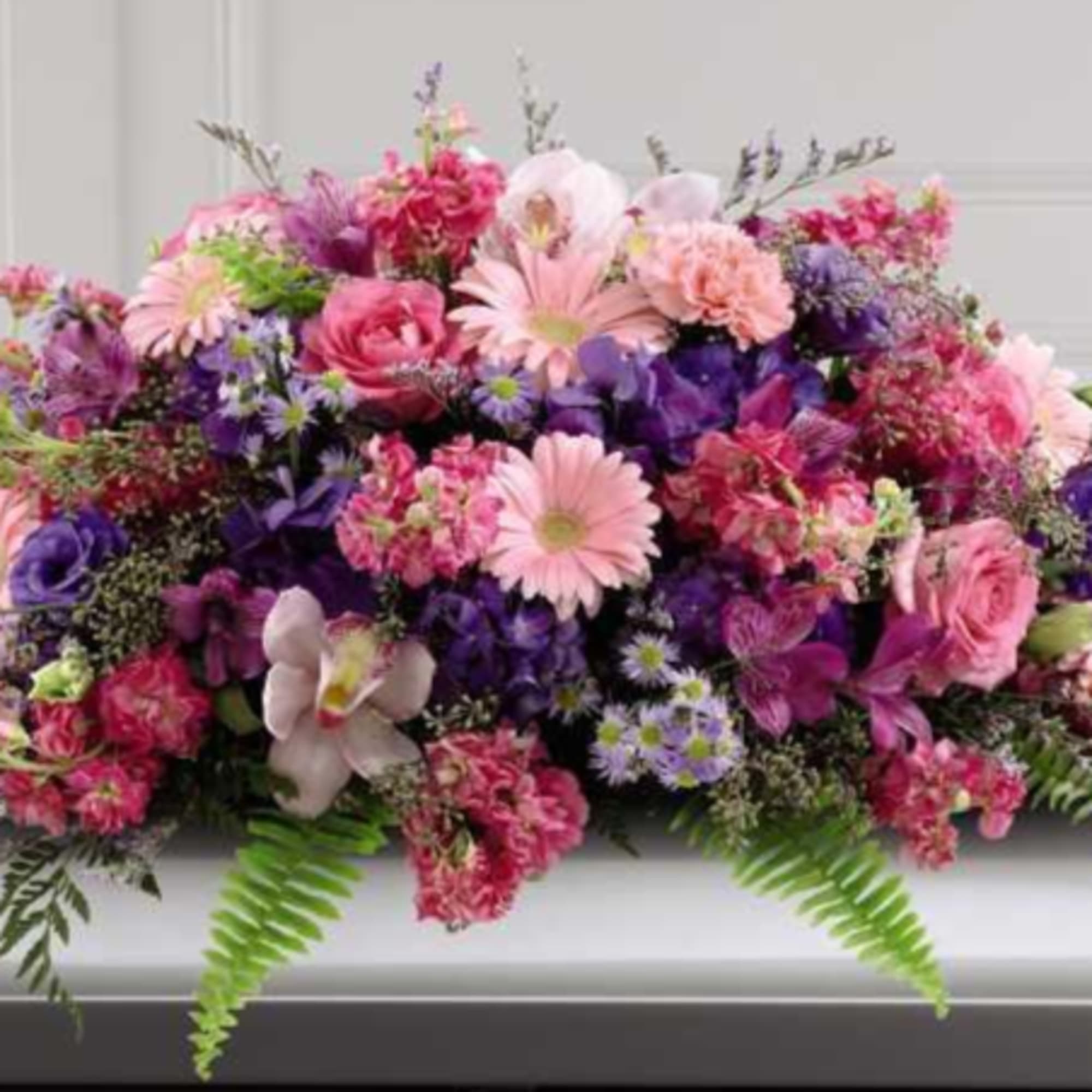 Large pink and purple floral spray on a casket