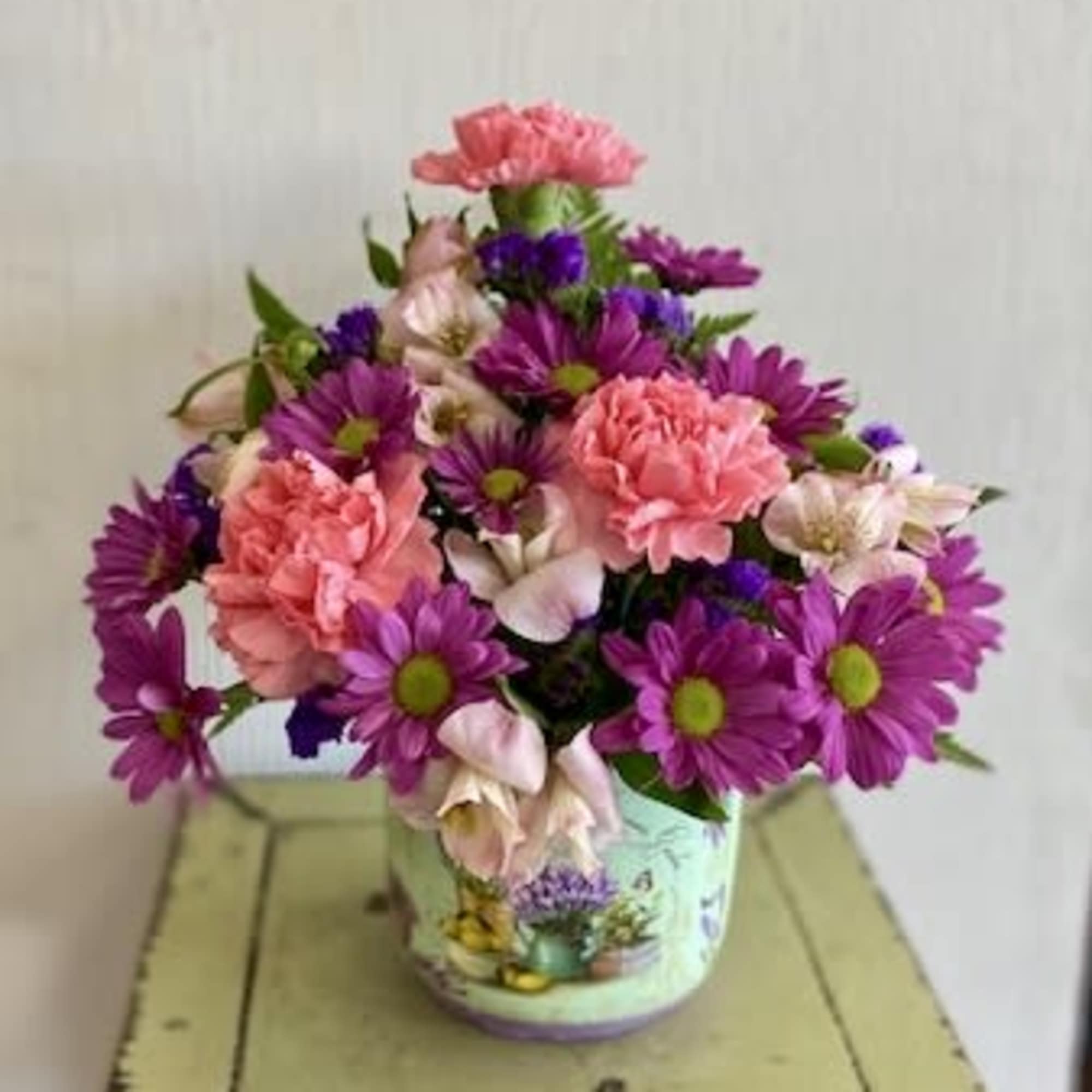 Pink and purple mixed bouquet in a decorative tin container