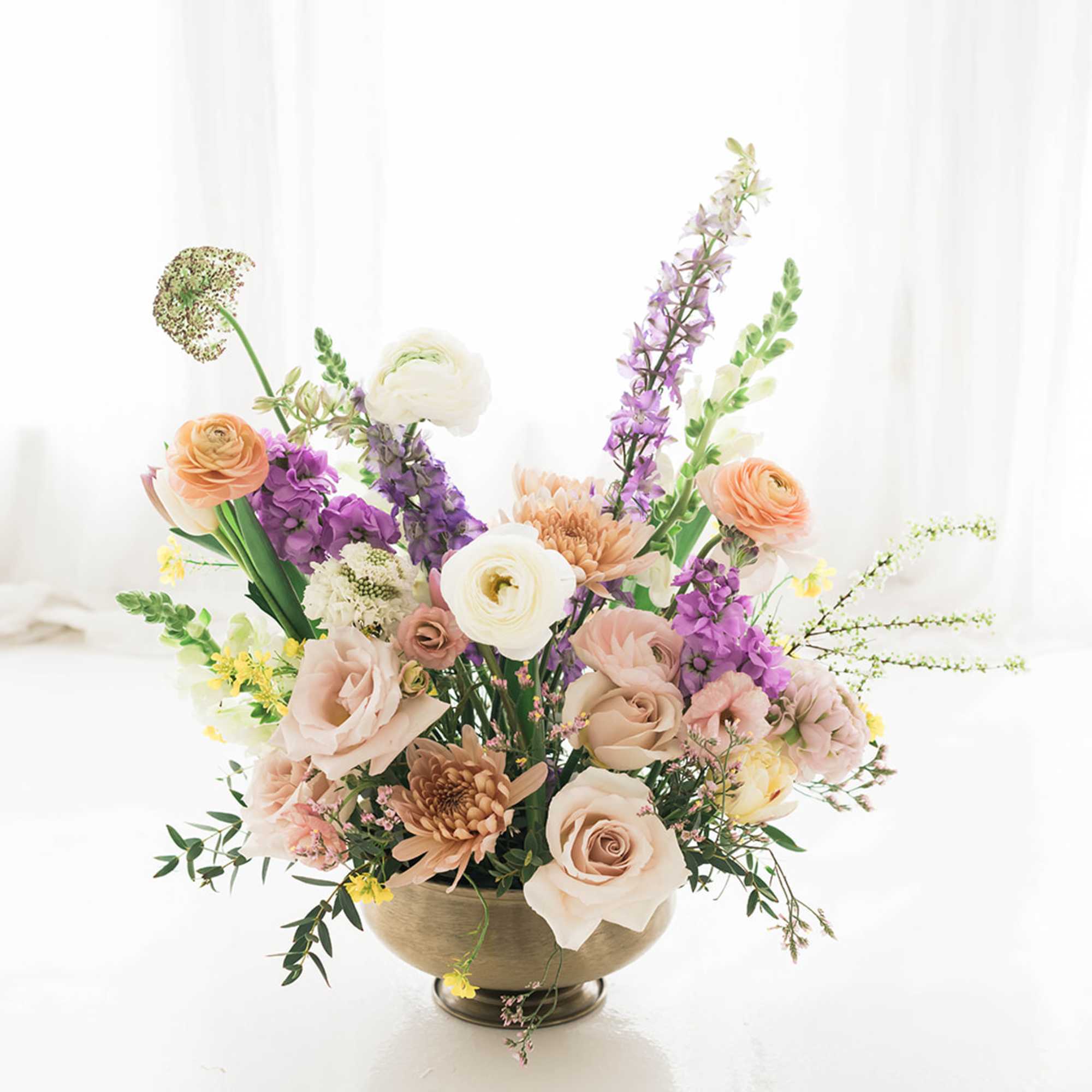 Mixed pastel flower arrangement in a gold bowl vase