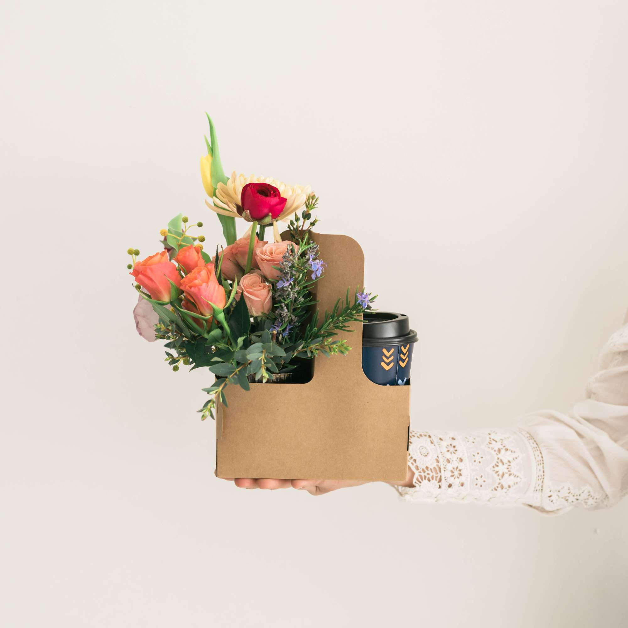 Handheld bouquet in a cardboard gift box with a coffee cup