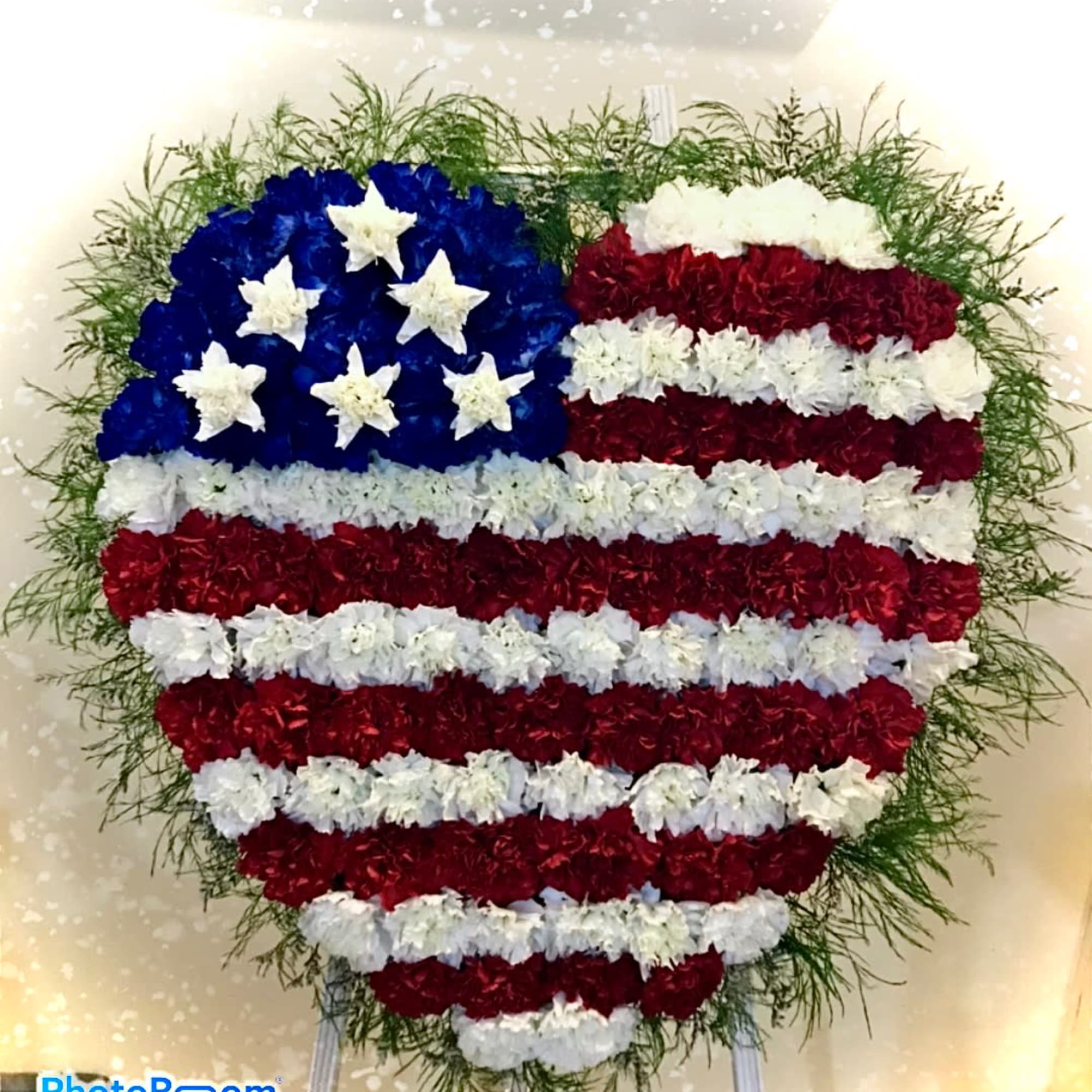 Heart-shaped standing floral wreath in red, white, and blue flag pattern with a green border.