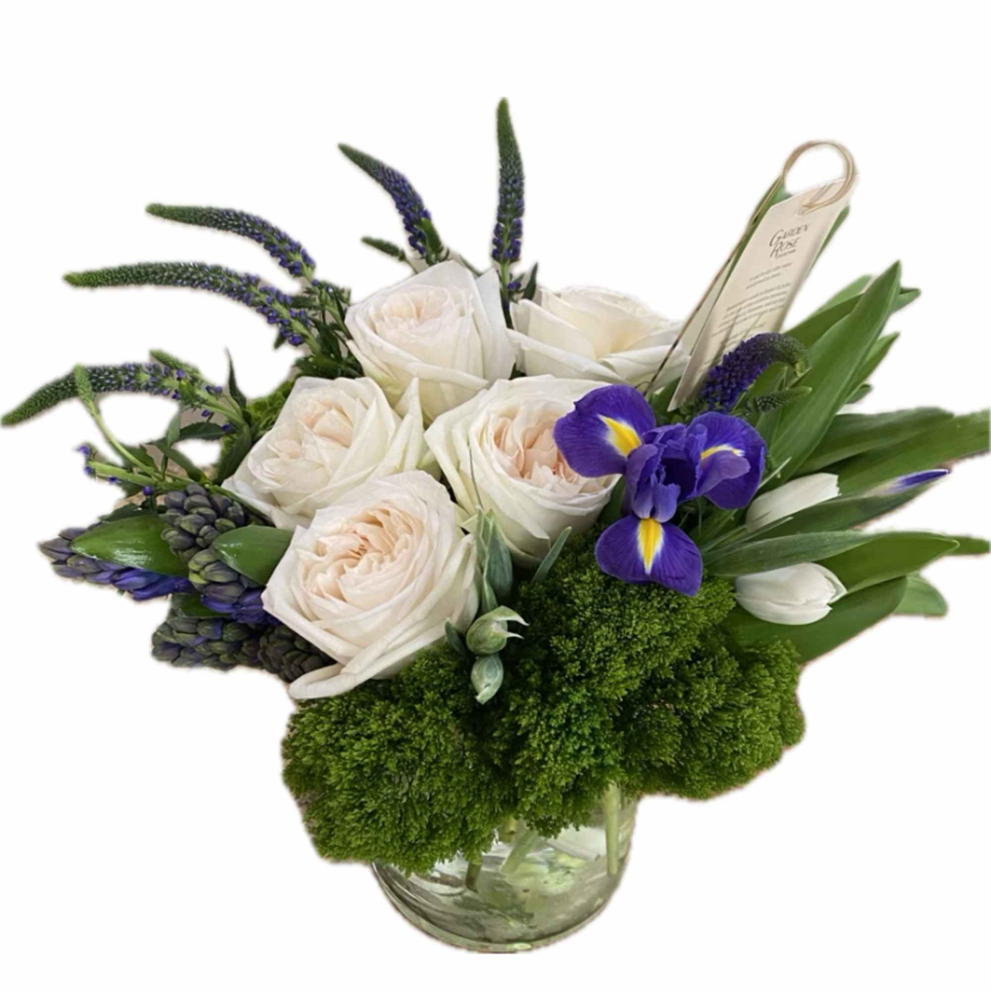Low glass vase with white roses, purple irises, white tulips, and green mossy accents