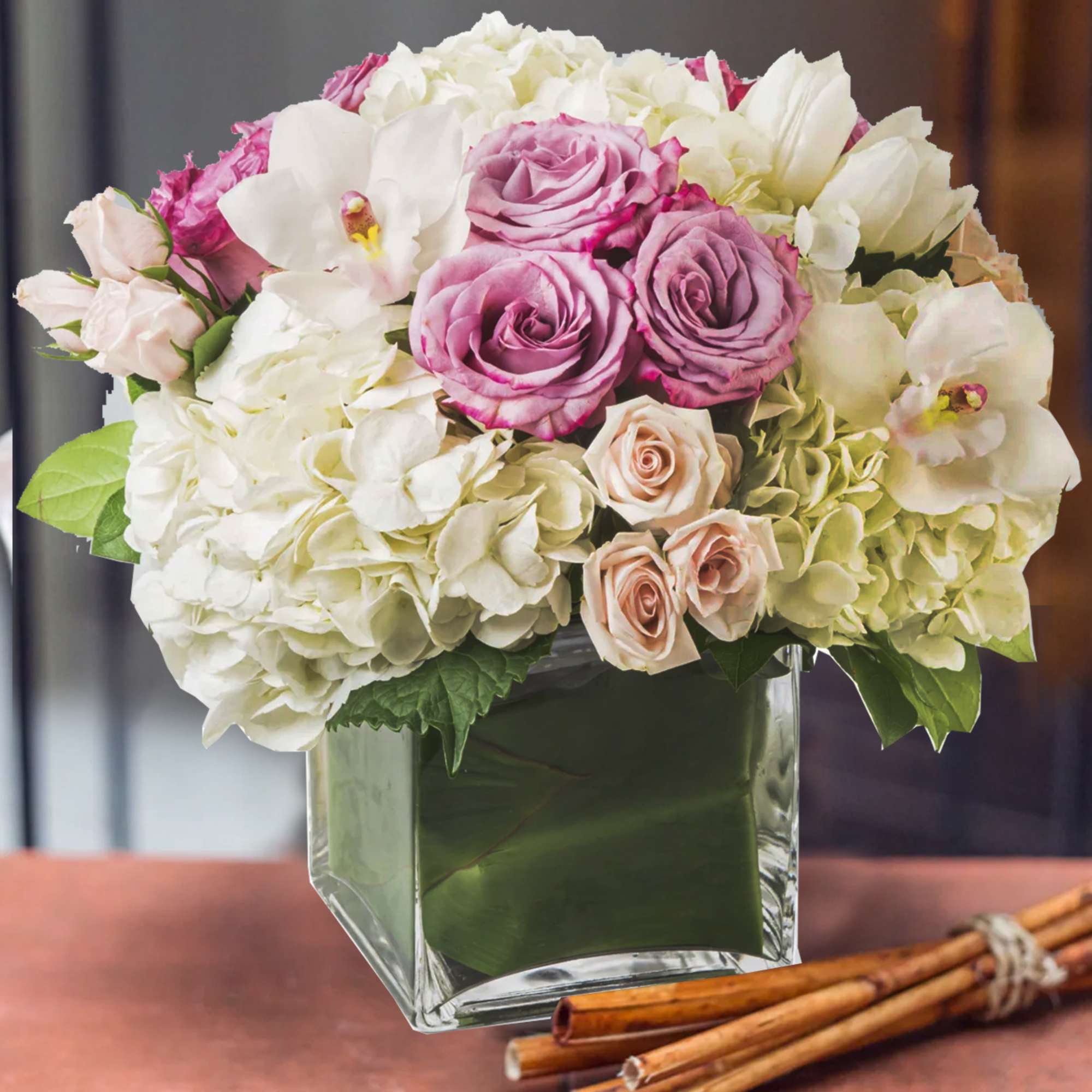 Pink and white roses with hydrangeas in a square glass vase