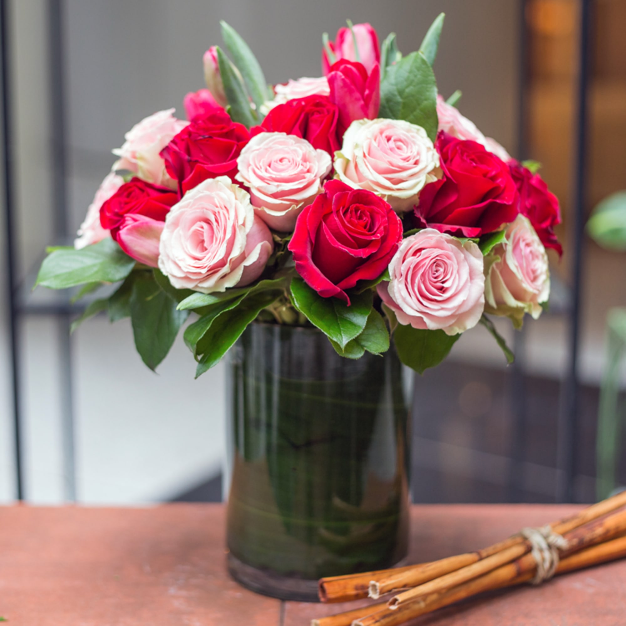 Bouquet of red and pale pink roses in a dark glass vase