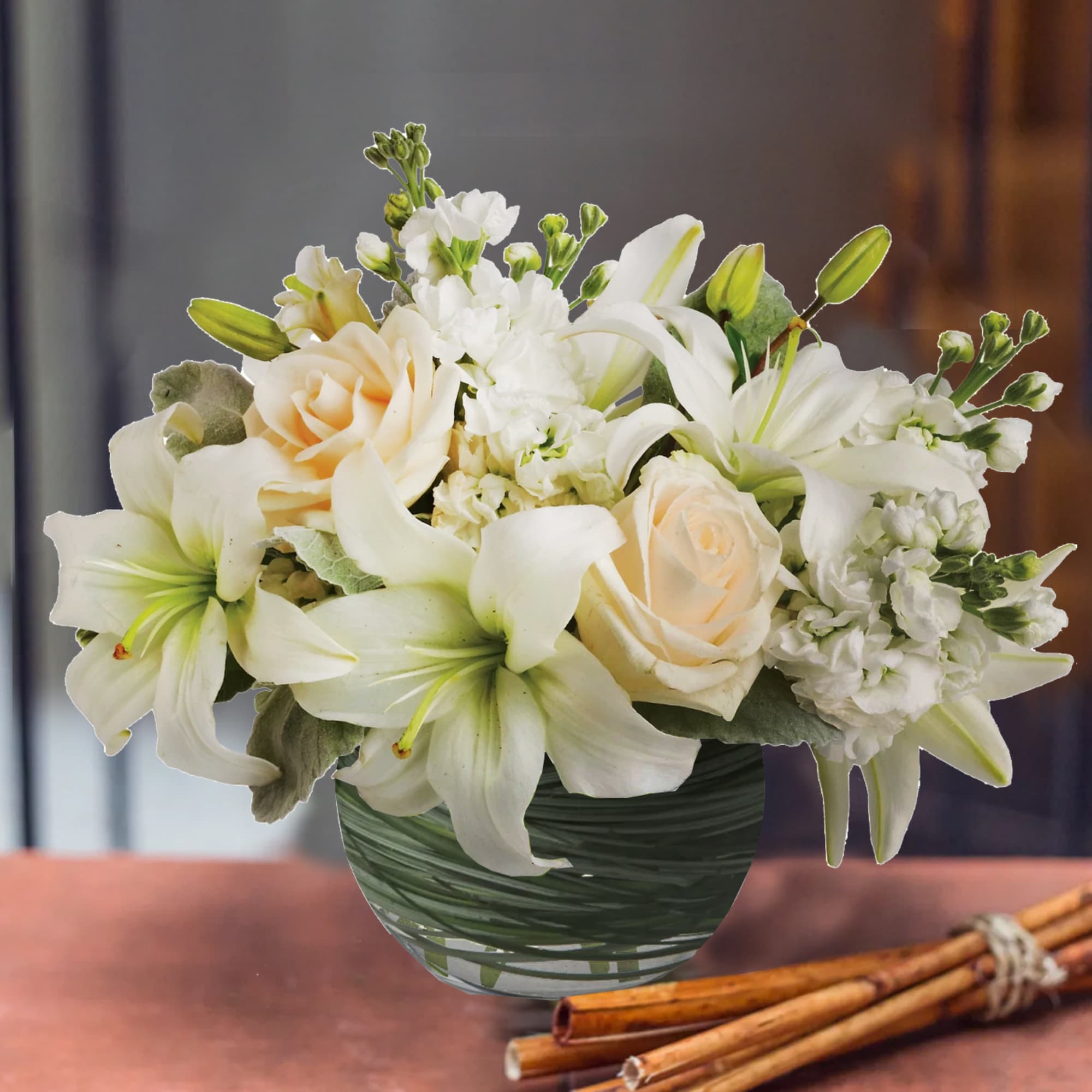 White lilies and cream roses arranged in a green glass vase