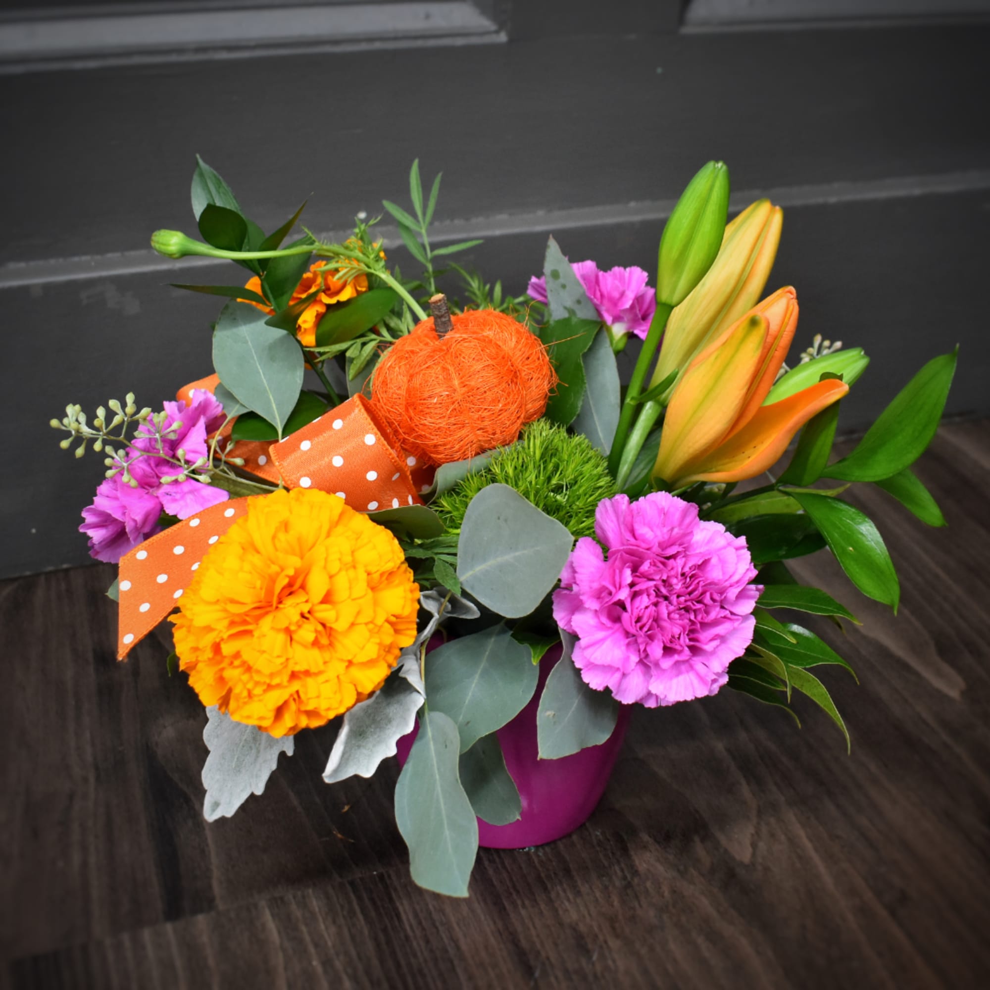 Colorful bouquet with orange lilies and pink carnations in a magenta vase