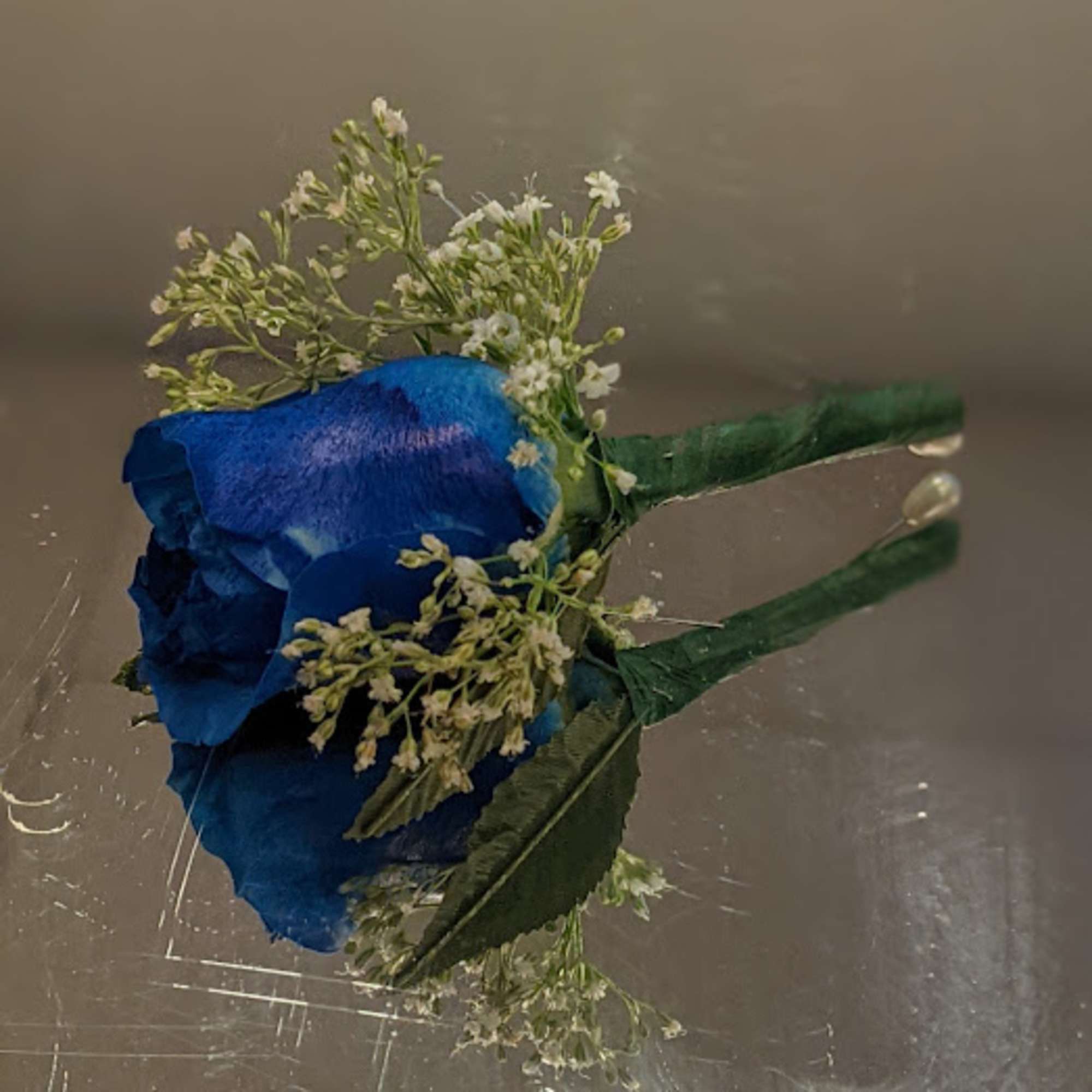 Blue rose boutonniere with small white filler flowers