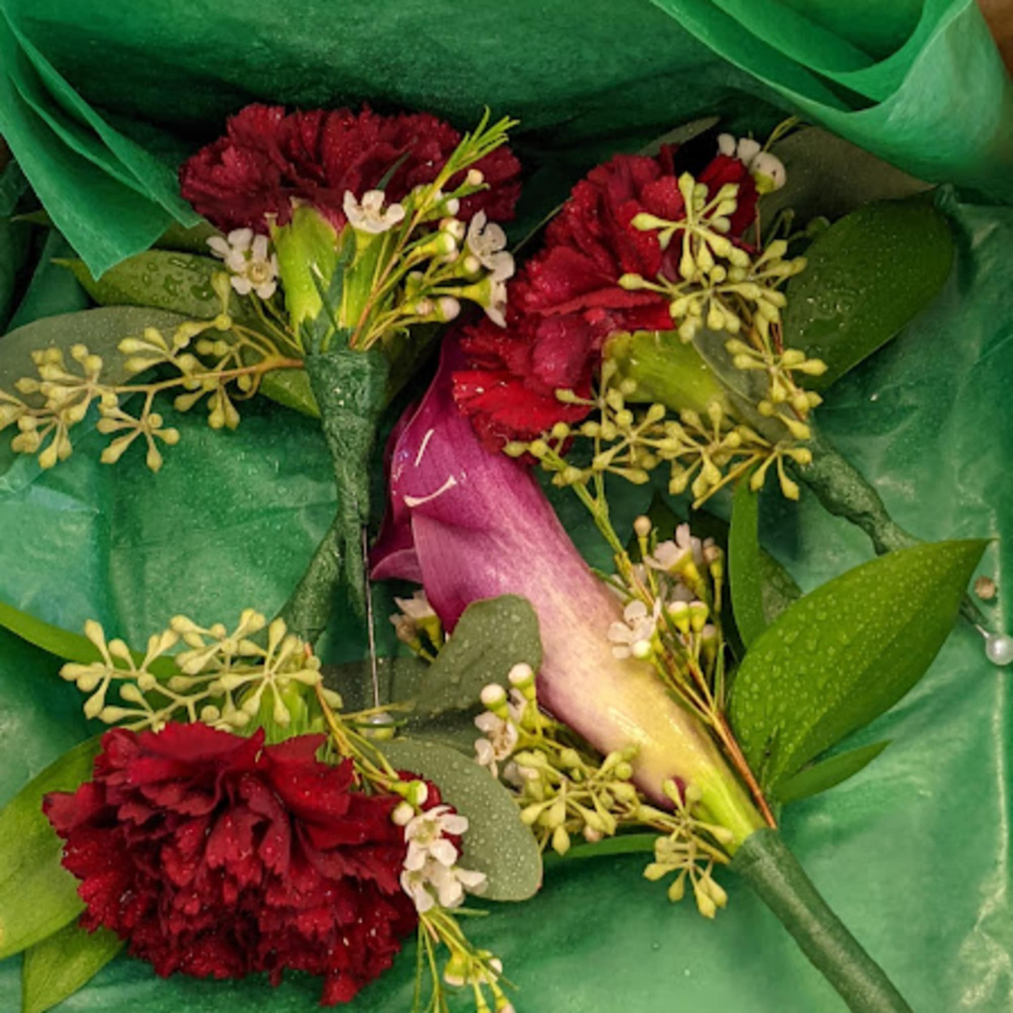 Small bouquet with red carnations and a purple calla lily in green wrap