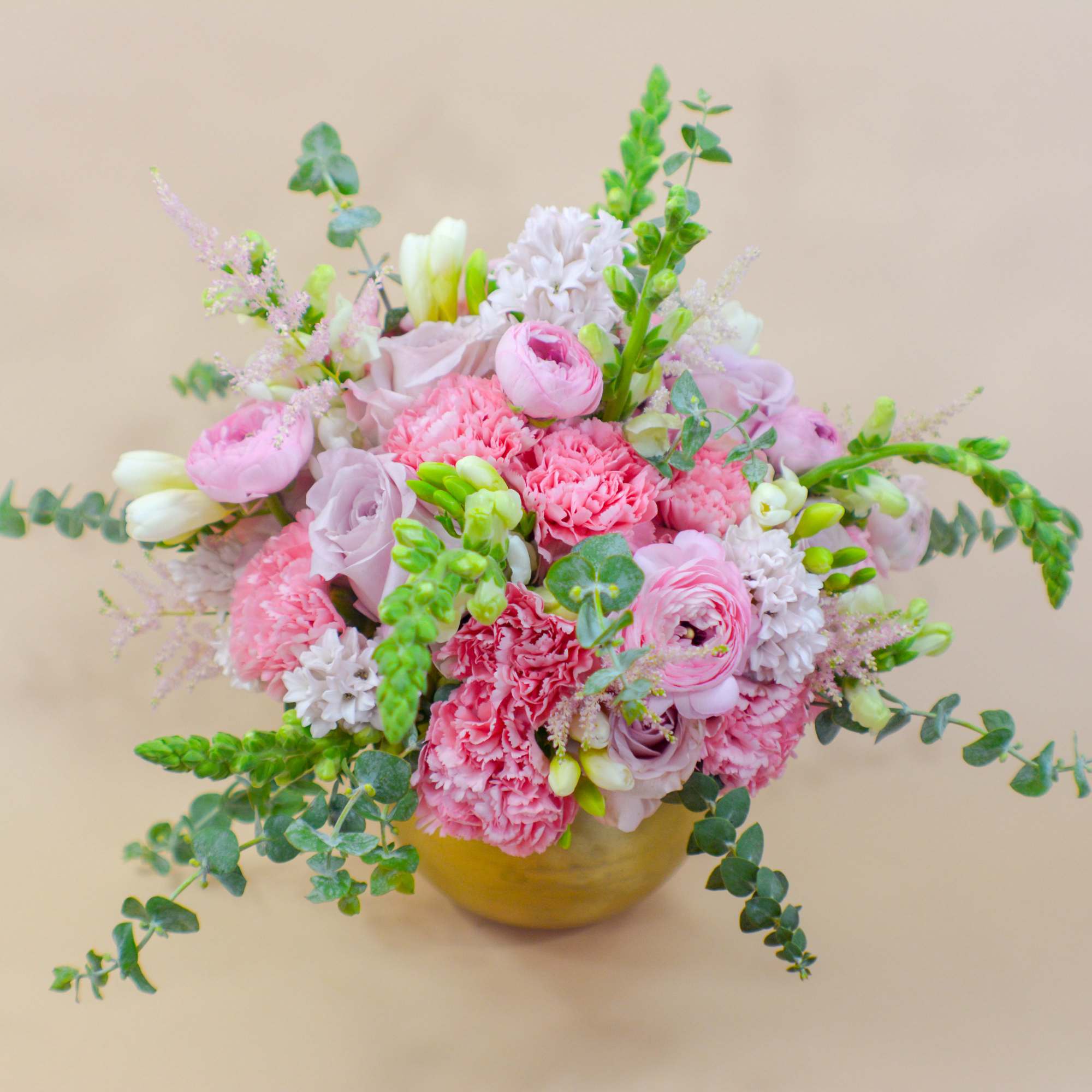 Pink mixed flower arrangement in a gold vase