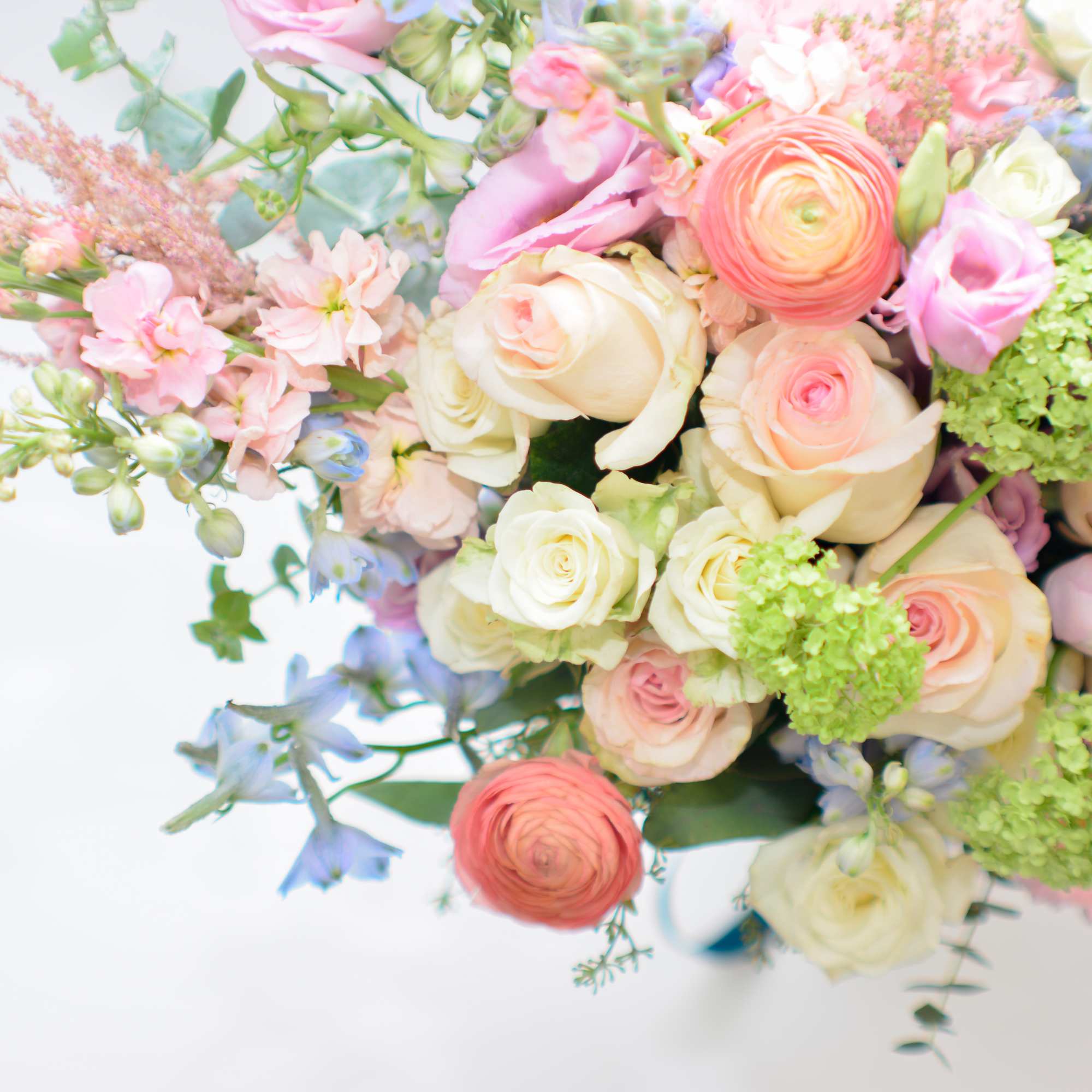 Pastel bouquet of roses, ranunculus, and small blue flowers