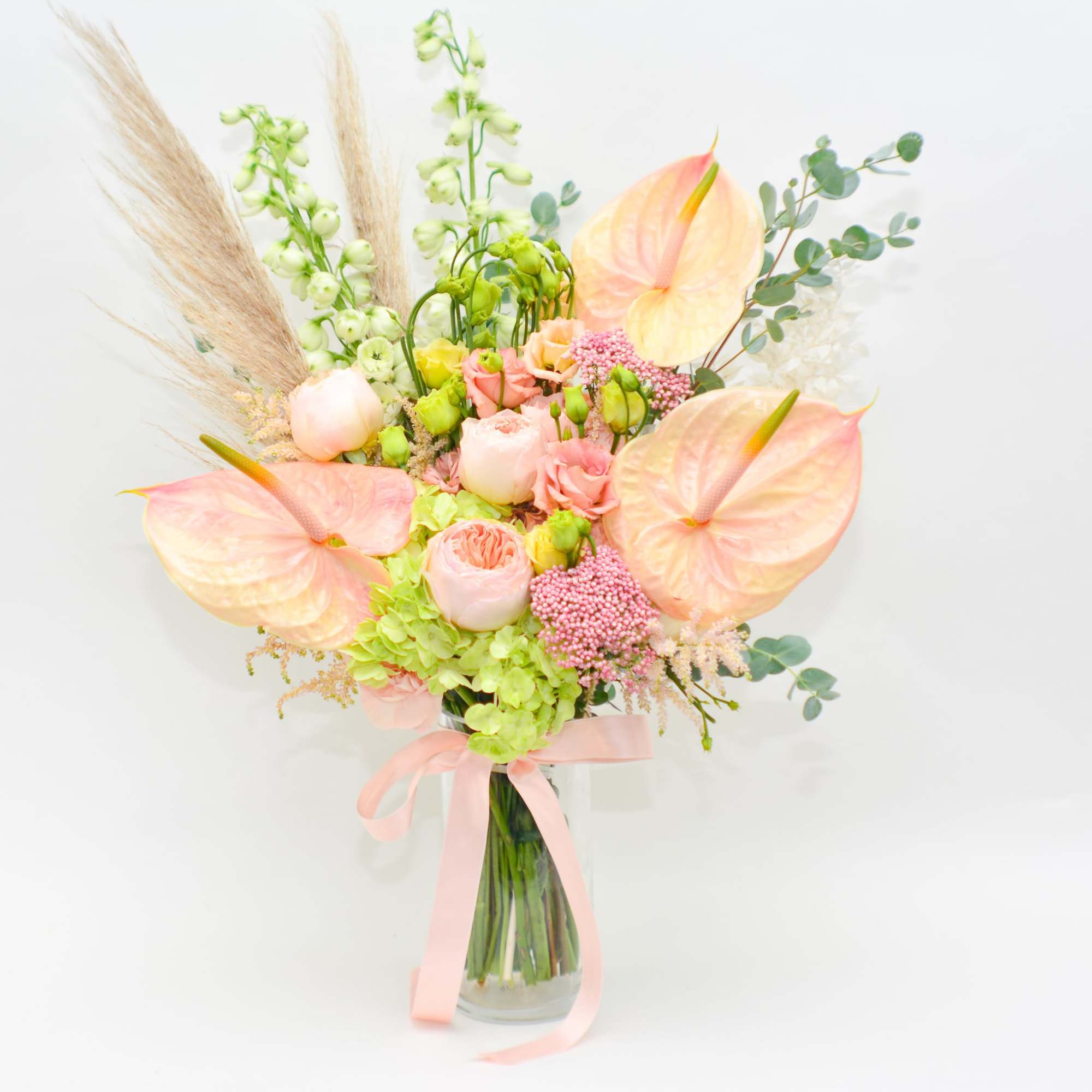 Pastel bouquet with anthuriums, roses, and a clear glass vase