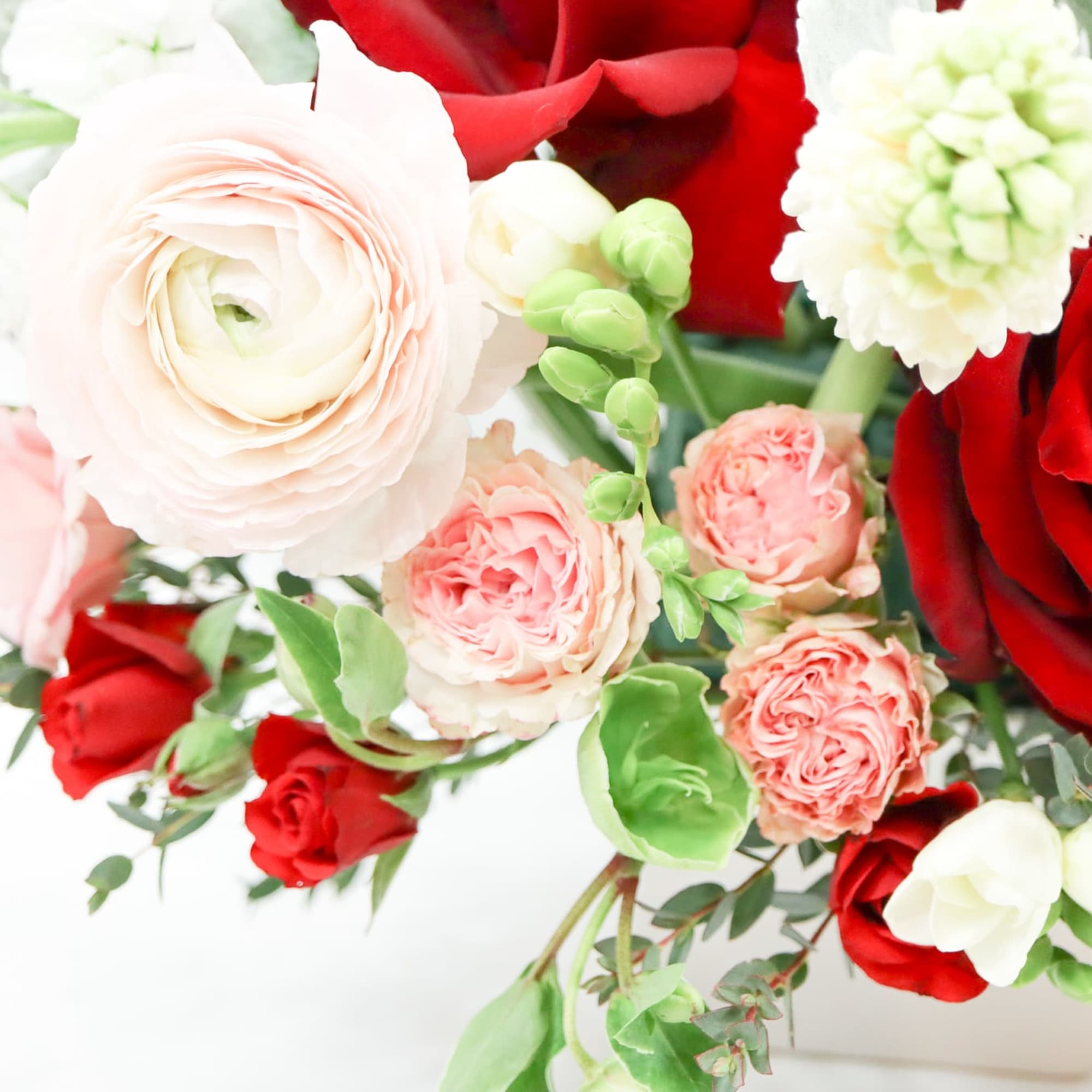 Bouquet of red and blush roses with white ranunculus and green accents