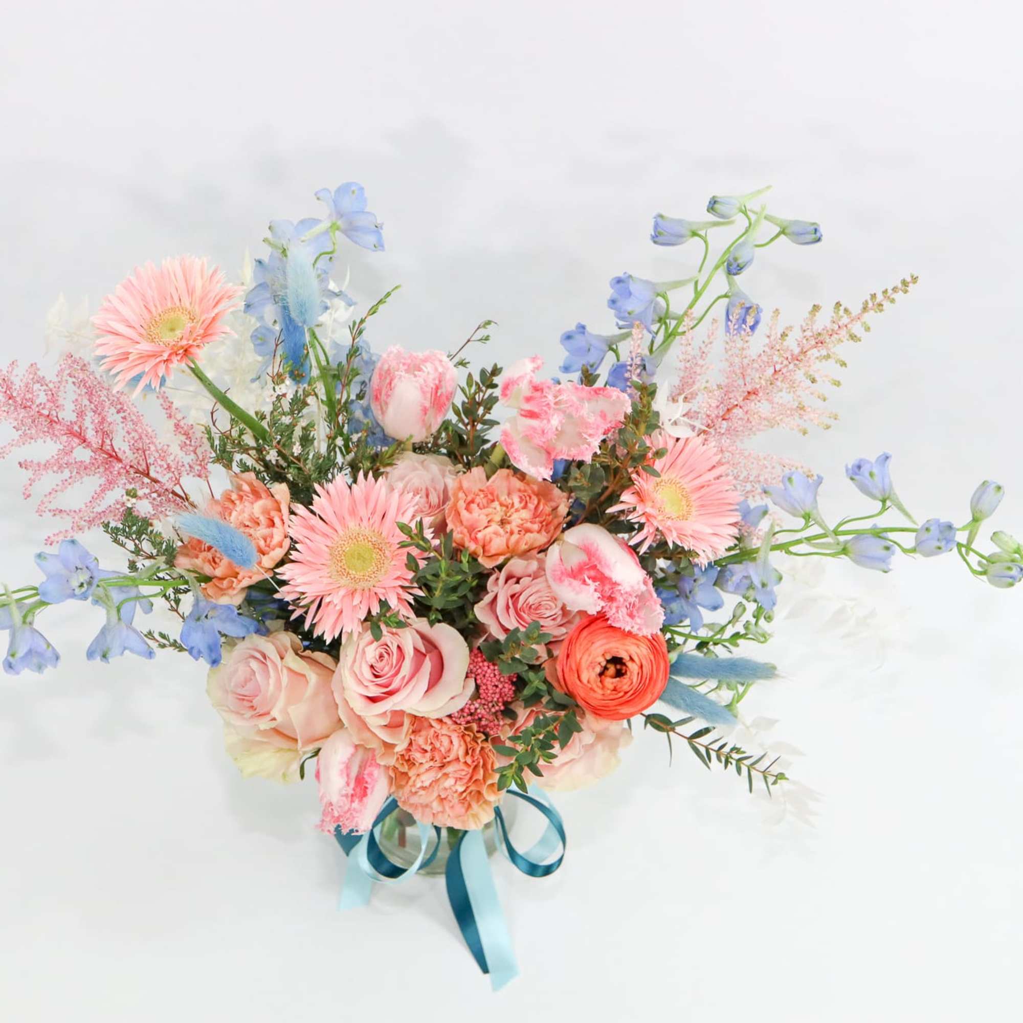 Pastel bouquet with pink and blue flowers tied with a blue ribbon