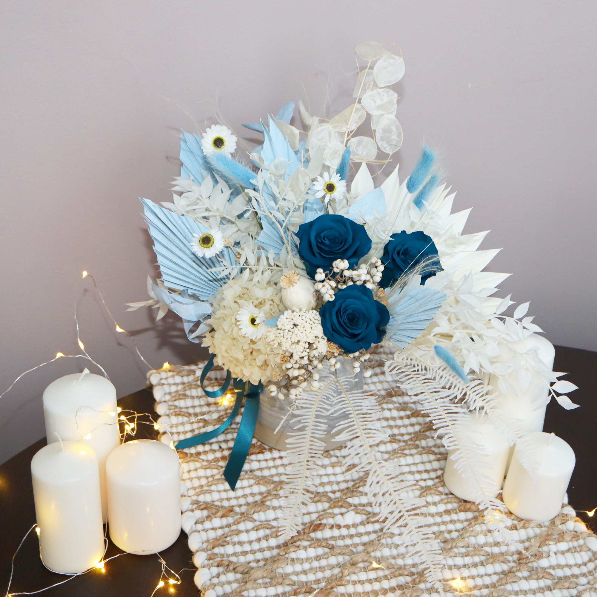 Blue and white floral arrangement with candles on a woven mat