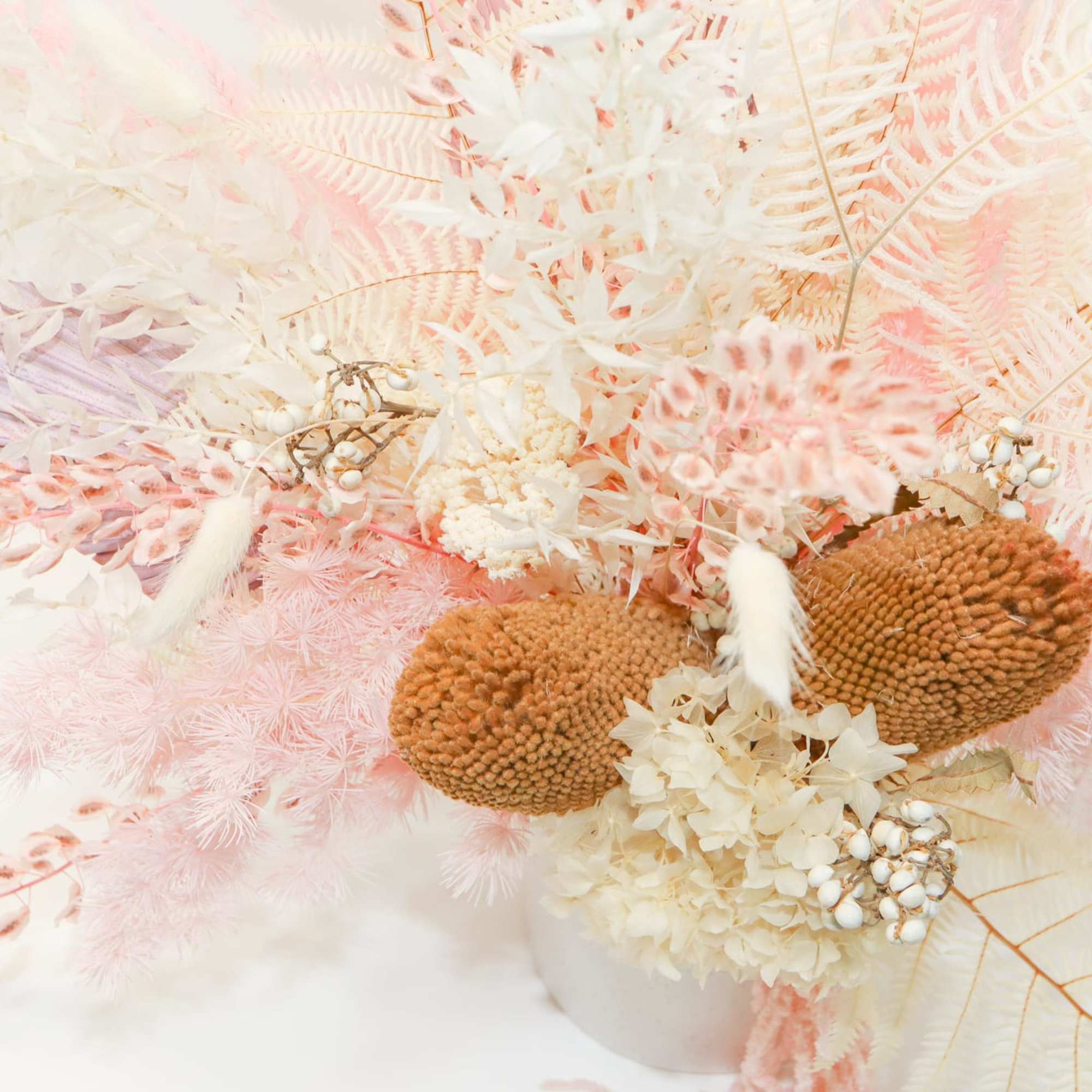 Pastel dried floral arrangement with cream, pink, and tan textures in a white vase