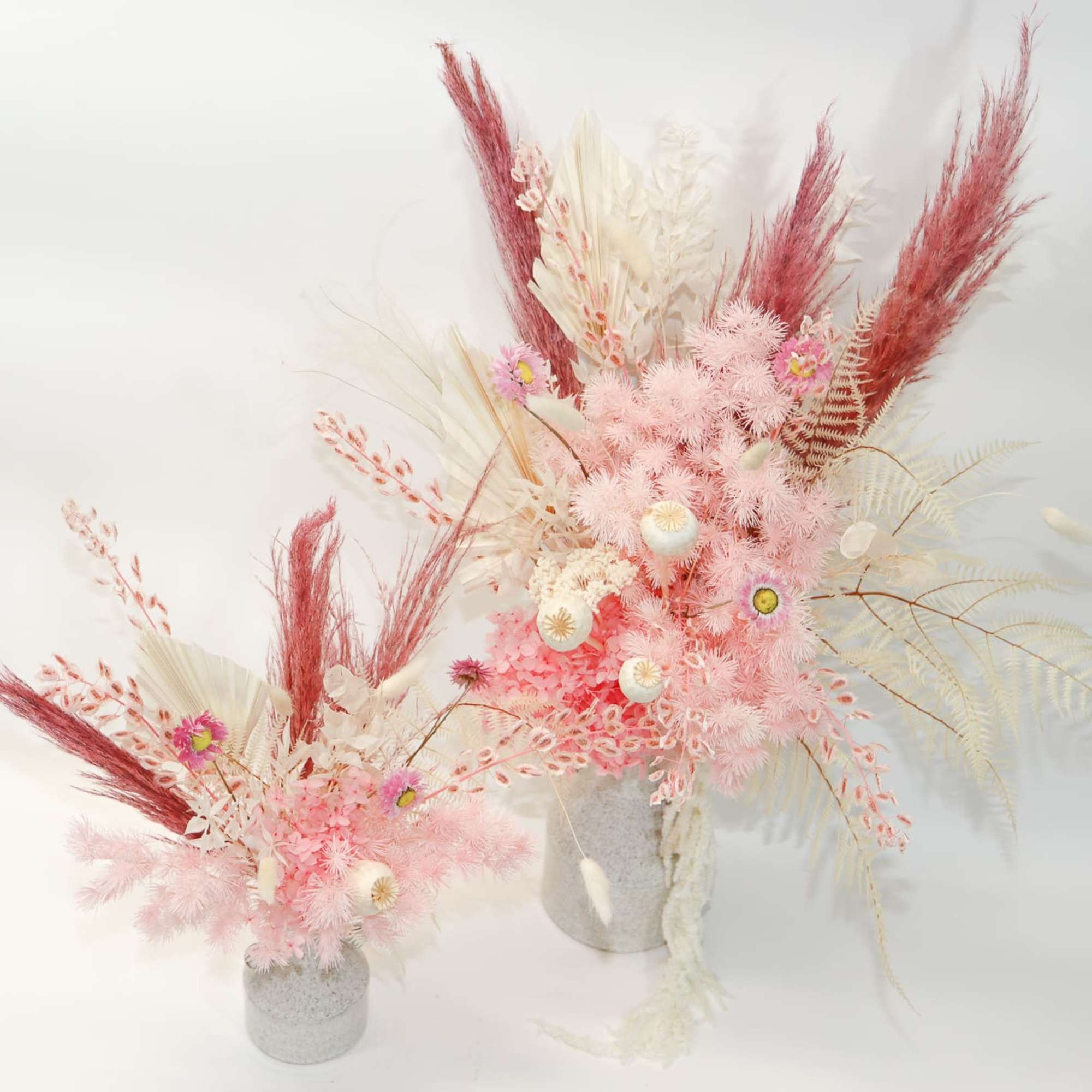 Pink and white dried floral arrangements in gray vases