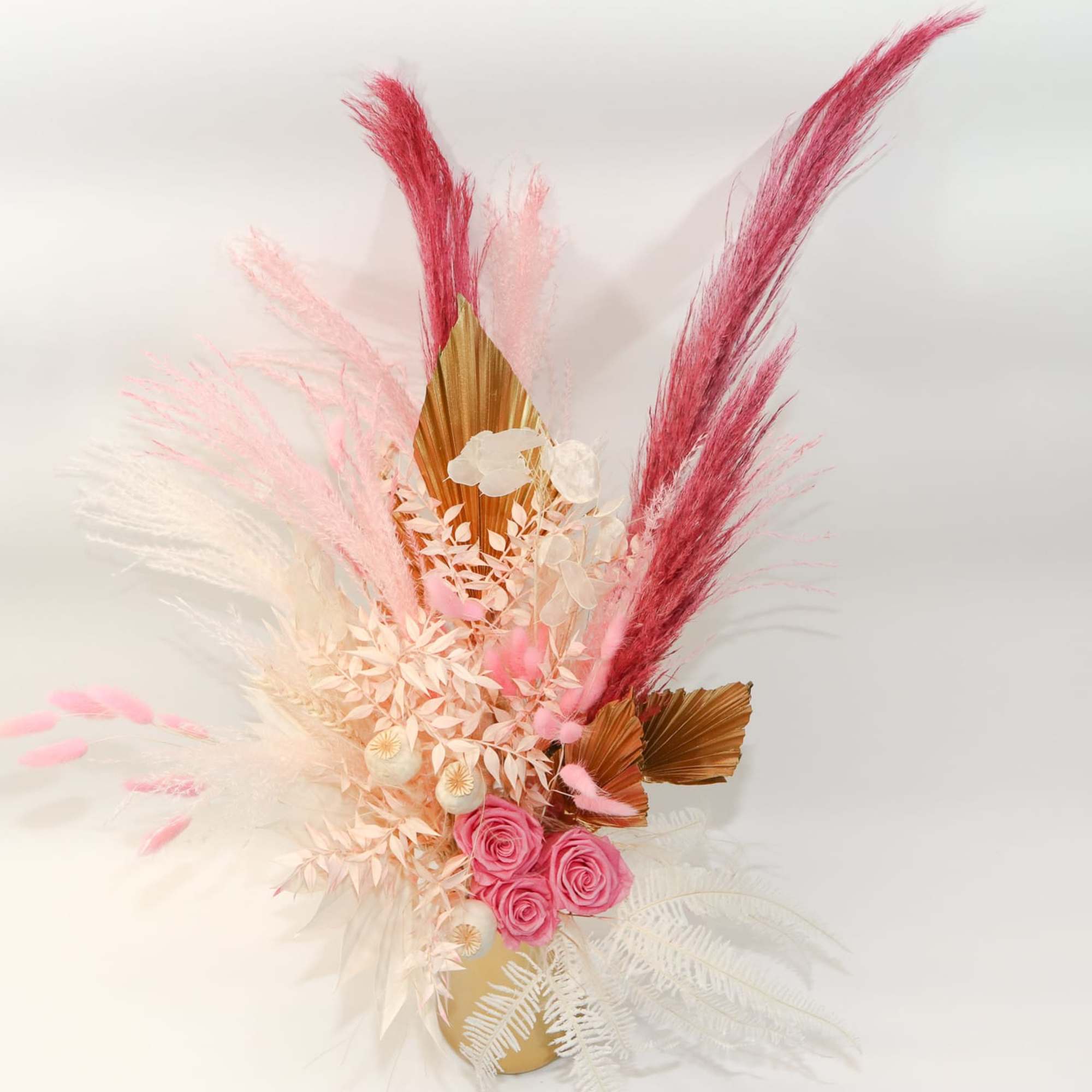 Pink roses with feathery pampas-style accents in a gold vase