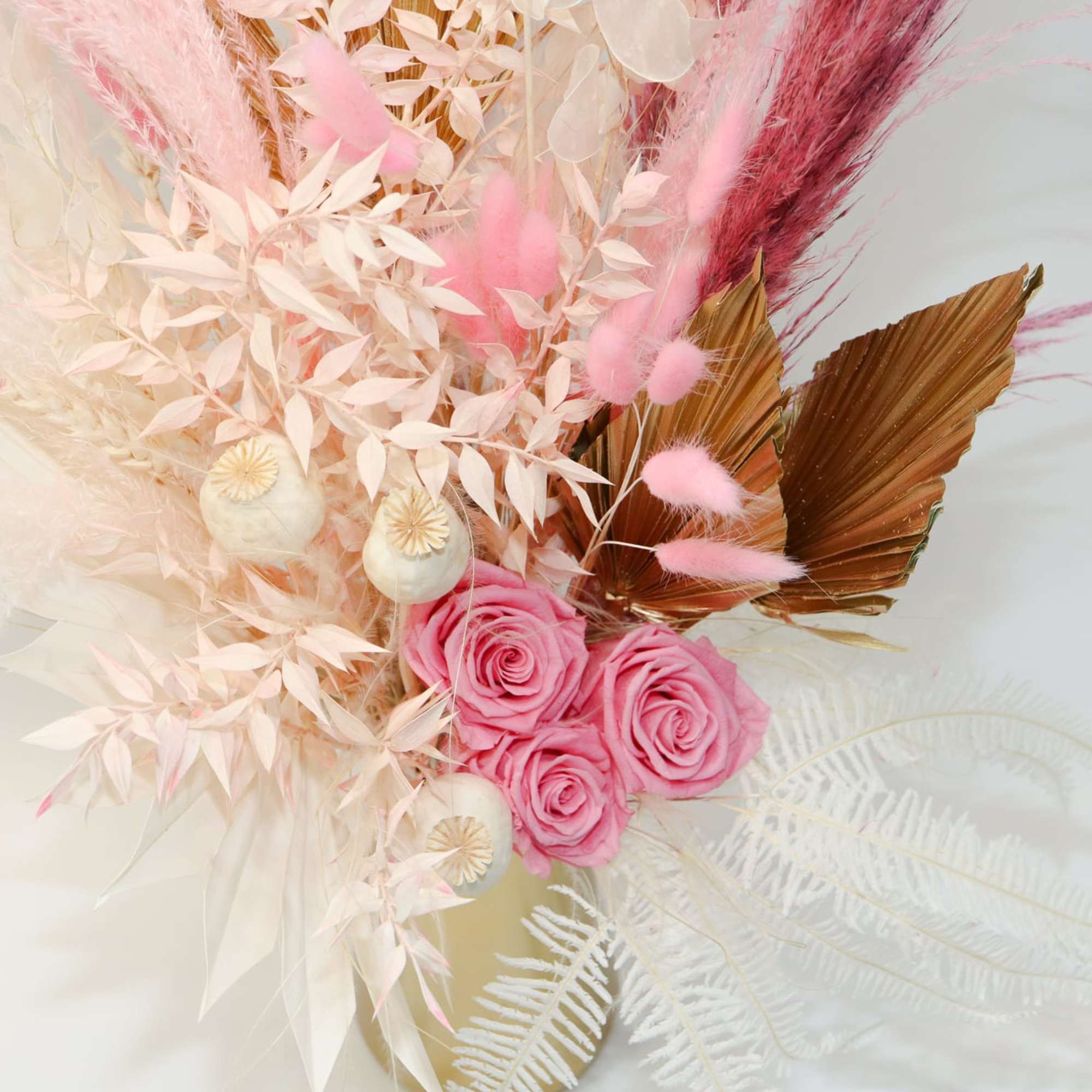 Pink roses with pale dried foliage and feathers in a decorative arrangement