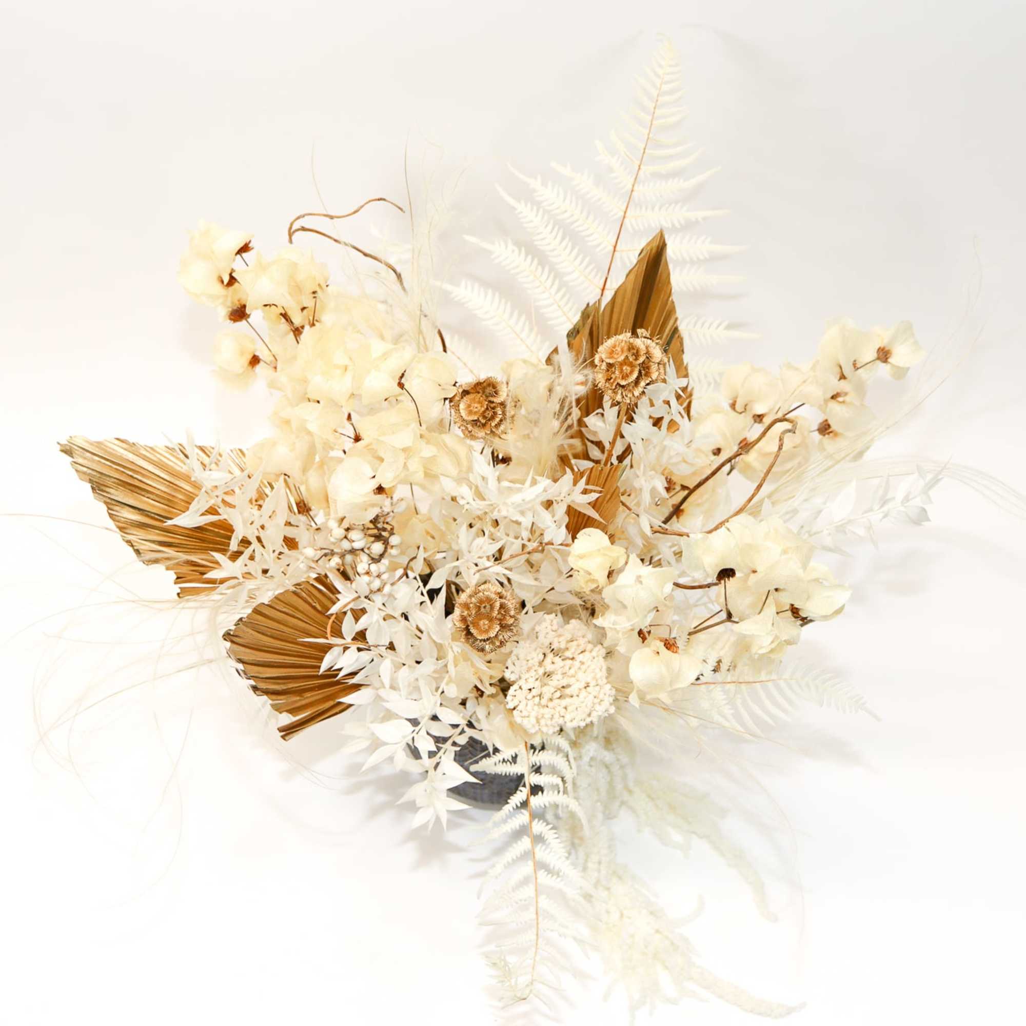 Cream floral arrangement with dried palm leaves and white feathery accents