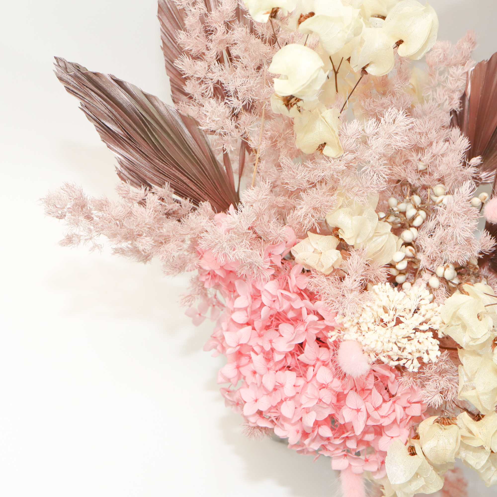 Pink and cream floral arrangement with dried palm leaves