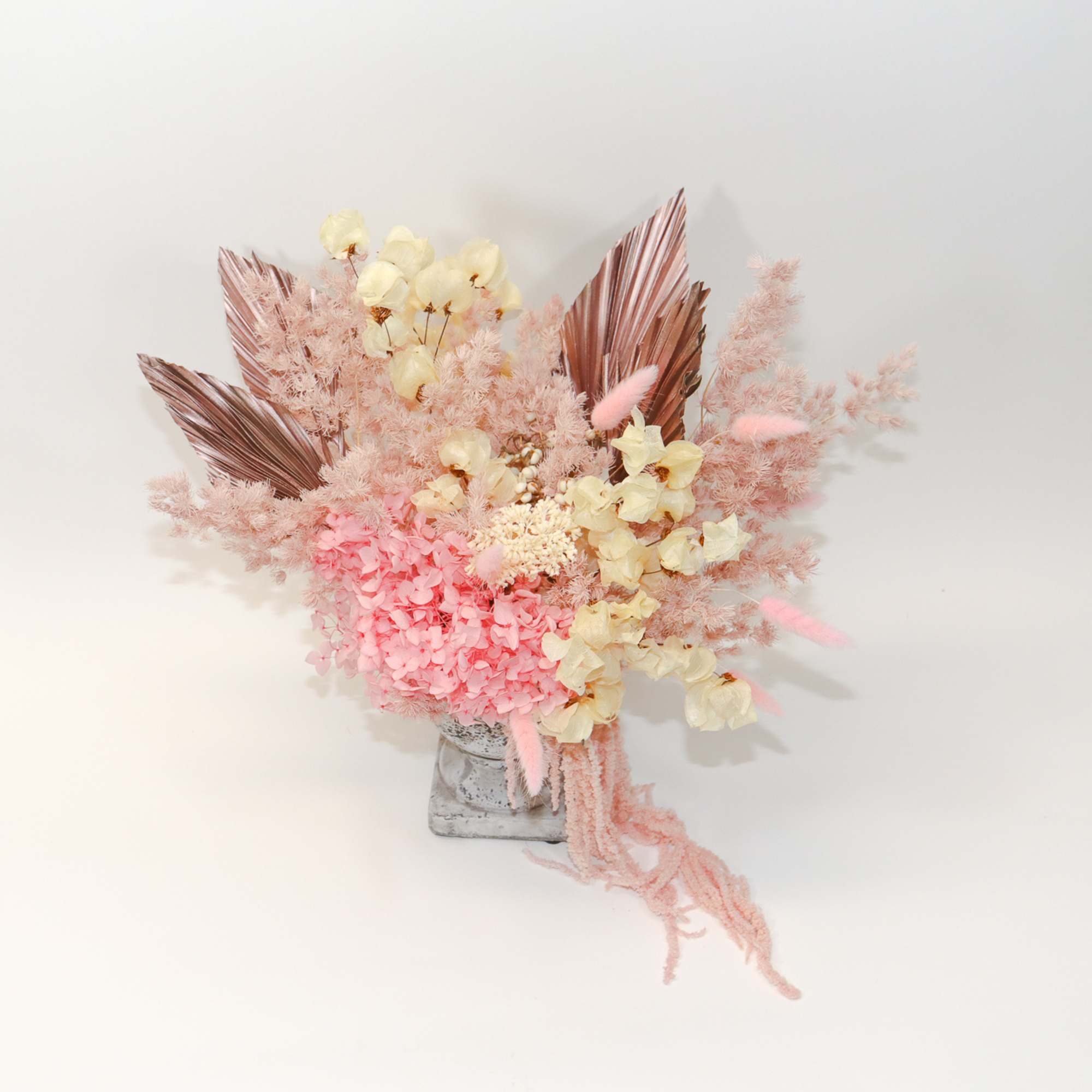 Pink and cream dried floral arrangement in a small vase