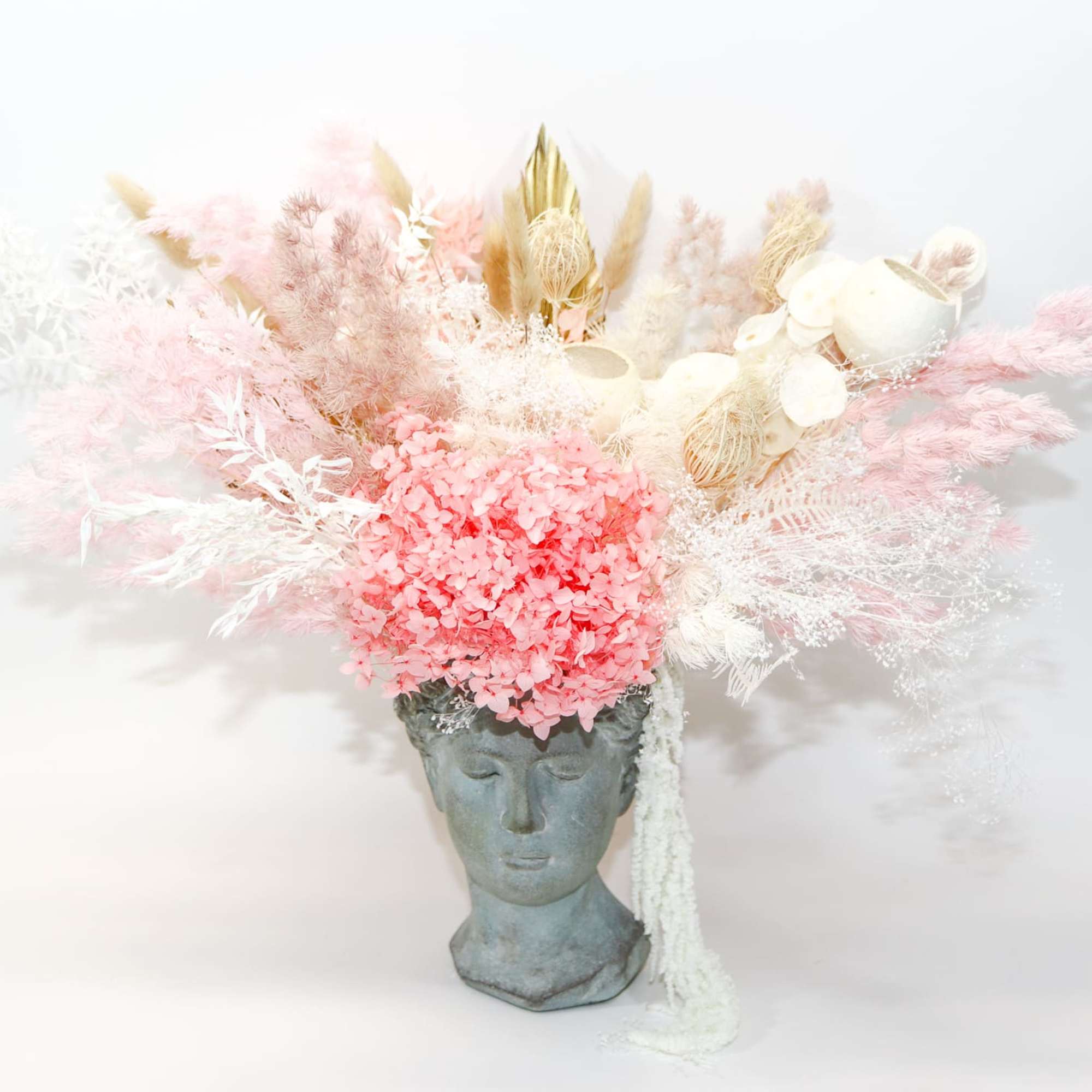 Pink and white dried floral arrangement in a sculpted face vase