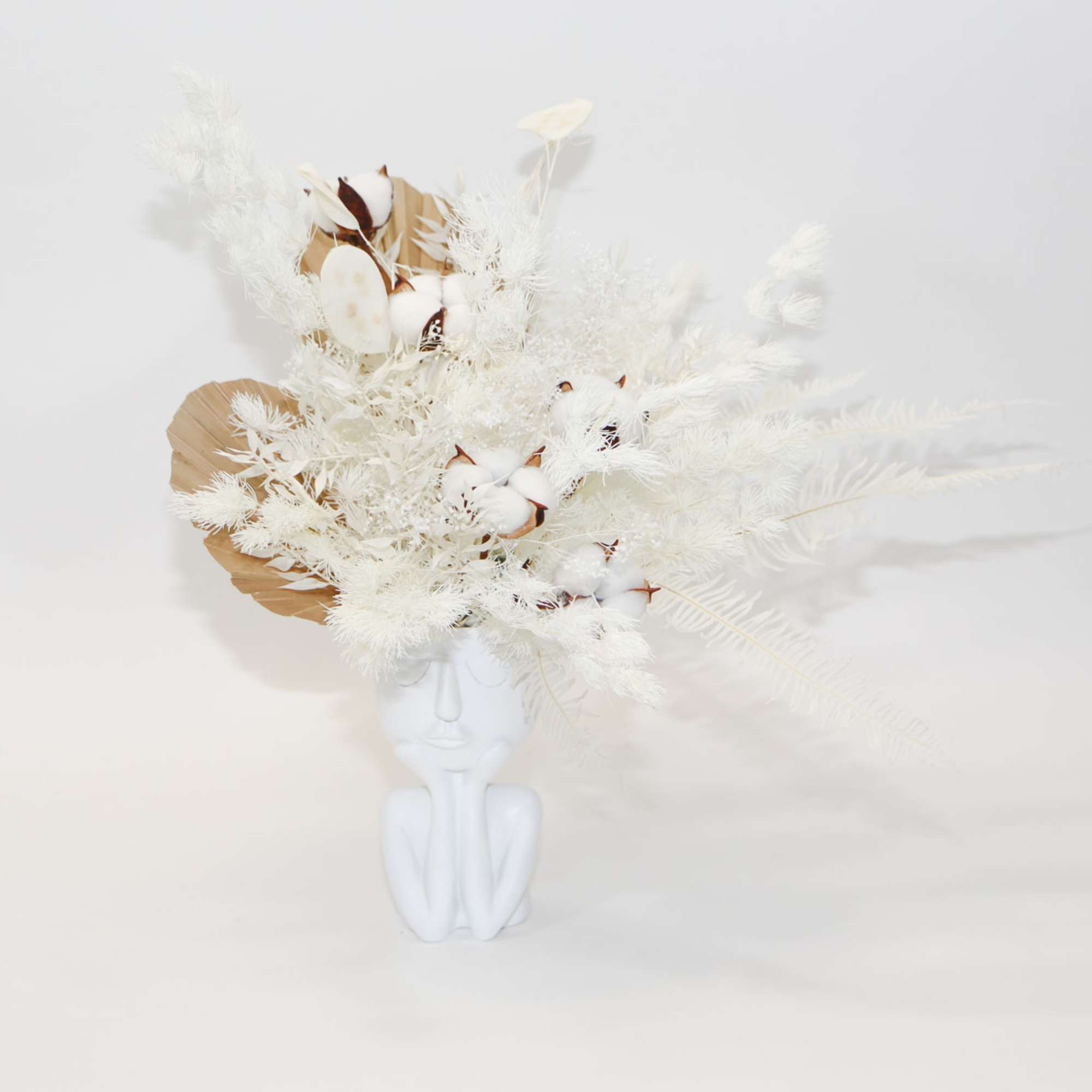 White floral arrangement in a white face-shaped vase