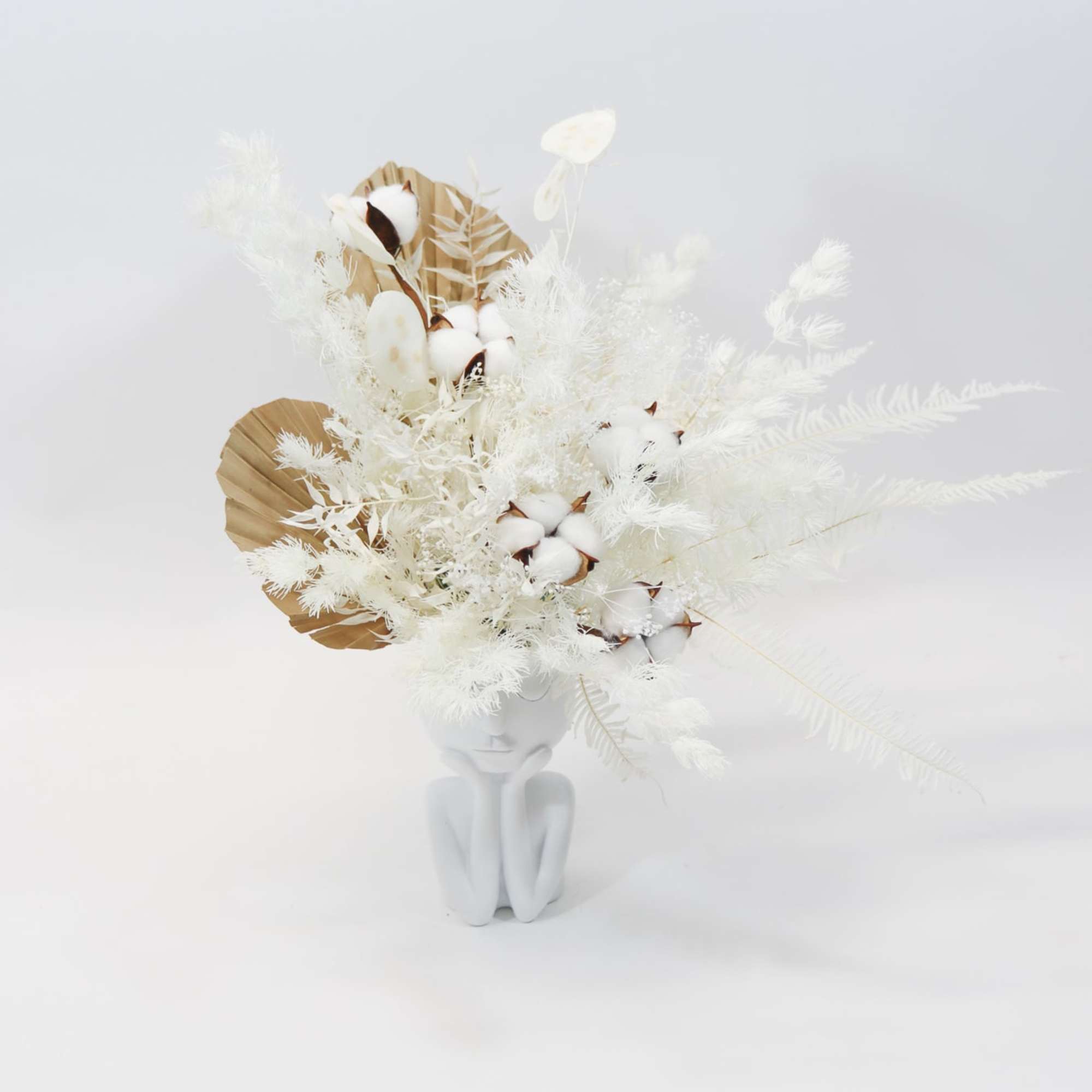 White dried floral arrangement in a sculptural white vase