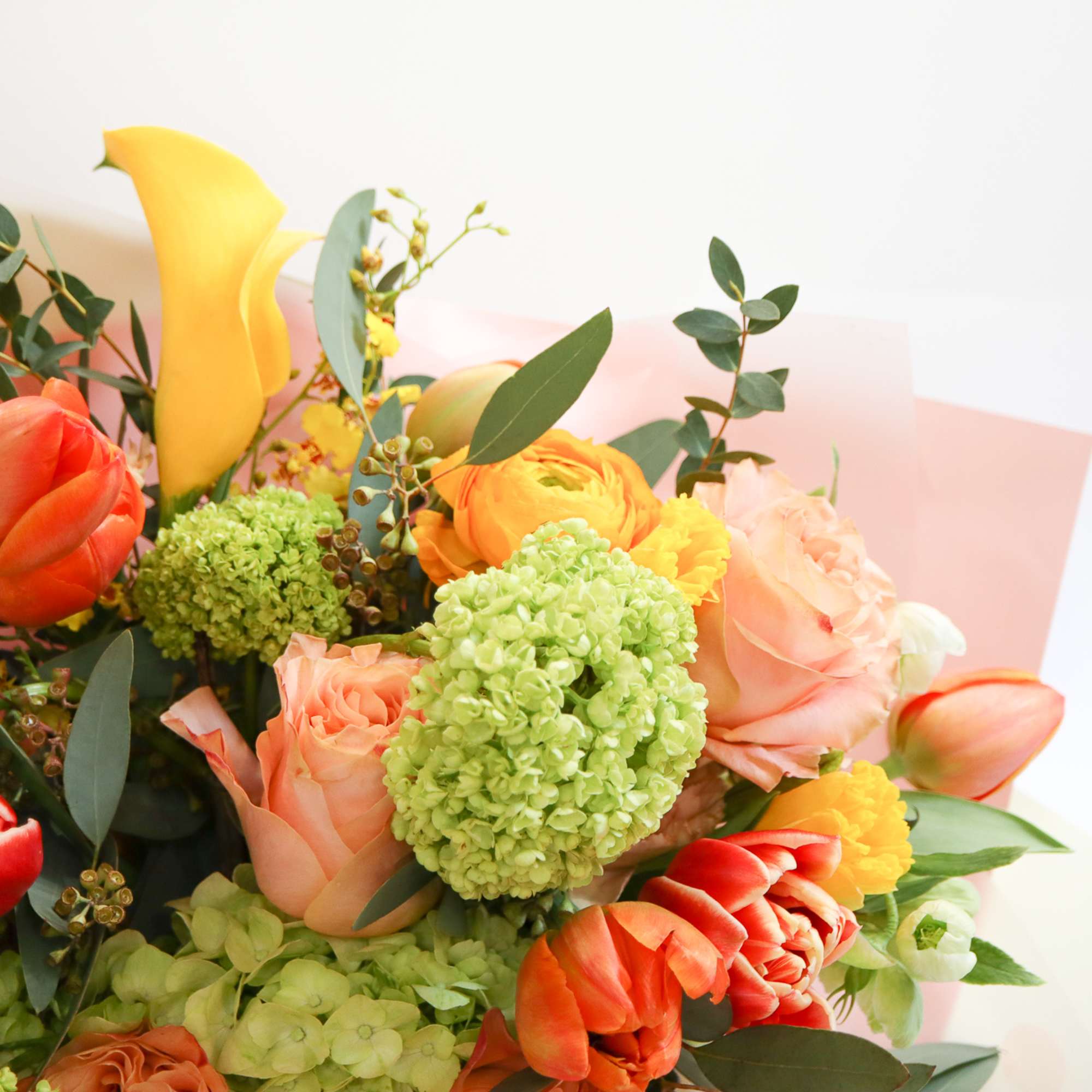 Bouquet of orange and peach flowers with green hydrangeas and yellow calla lilies