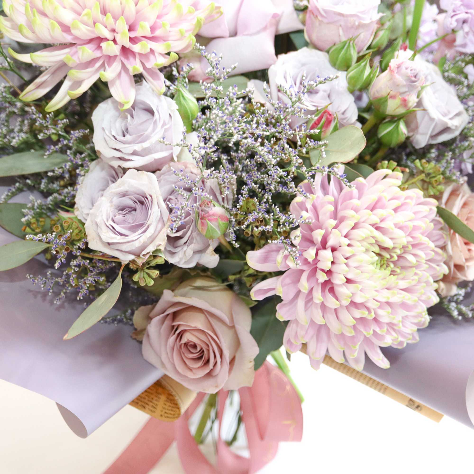 Bouquet of pale pink roses and chrysanthemums wrapped in lavender paper