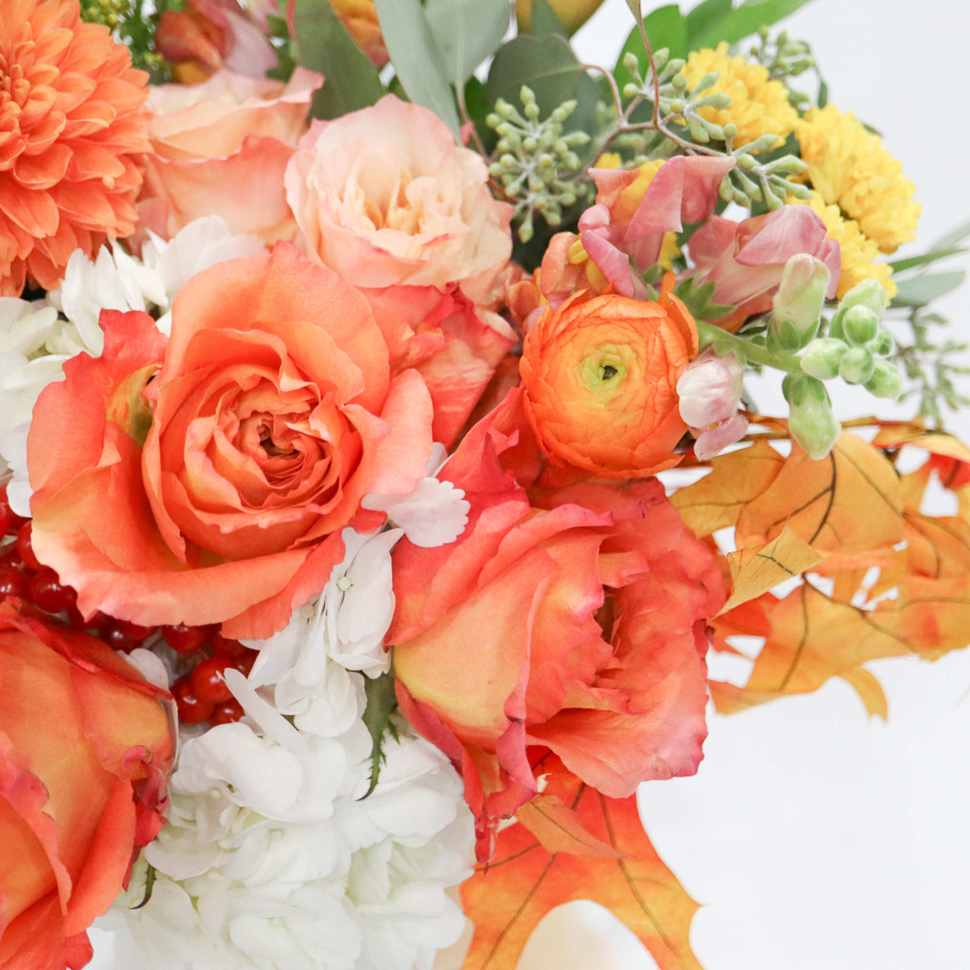 Orange and white floral bouquet with autumn leaves and red berries