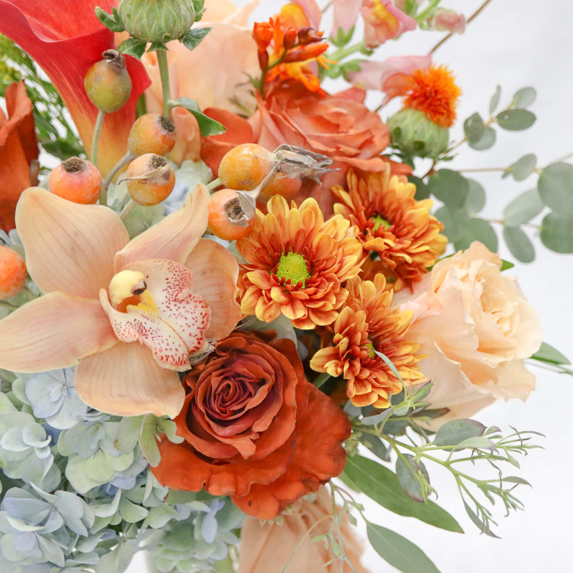 Orange and peach bouquet with roses, orchids, and chrysanthemums