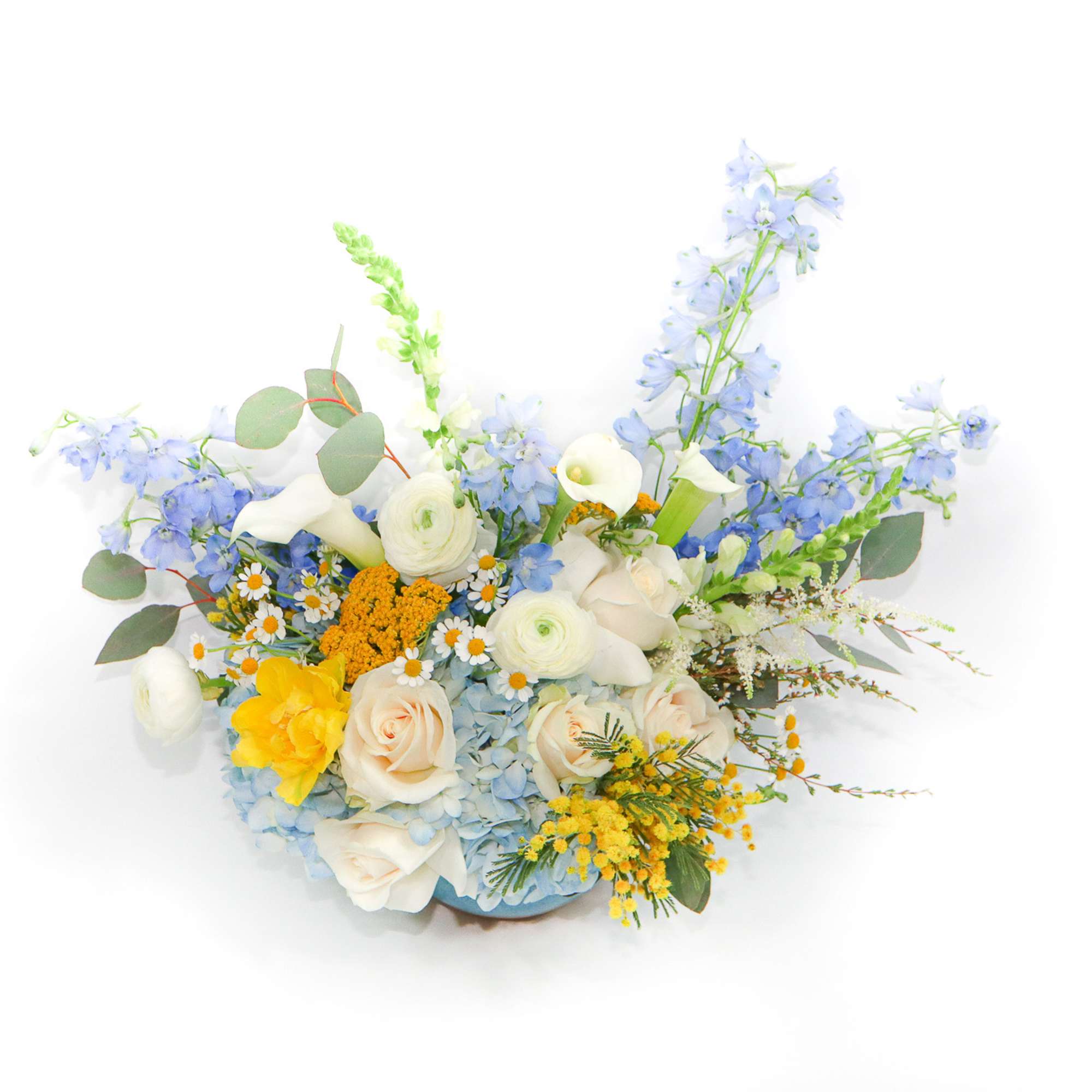 Mixed bouquet with blue, white, and yellow flowers in a low container
