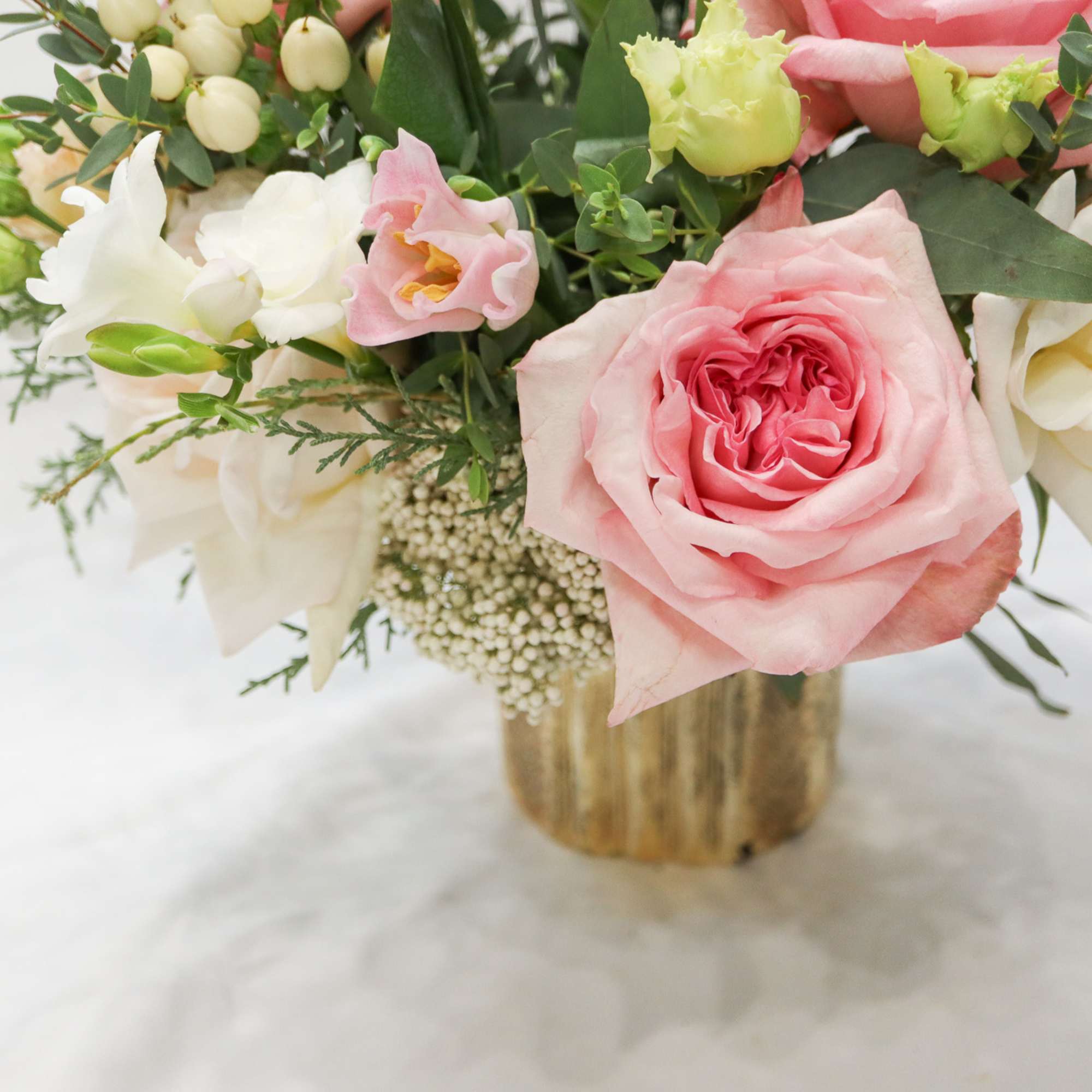 Pink and white roses arranged in a gold vase