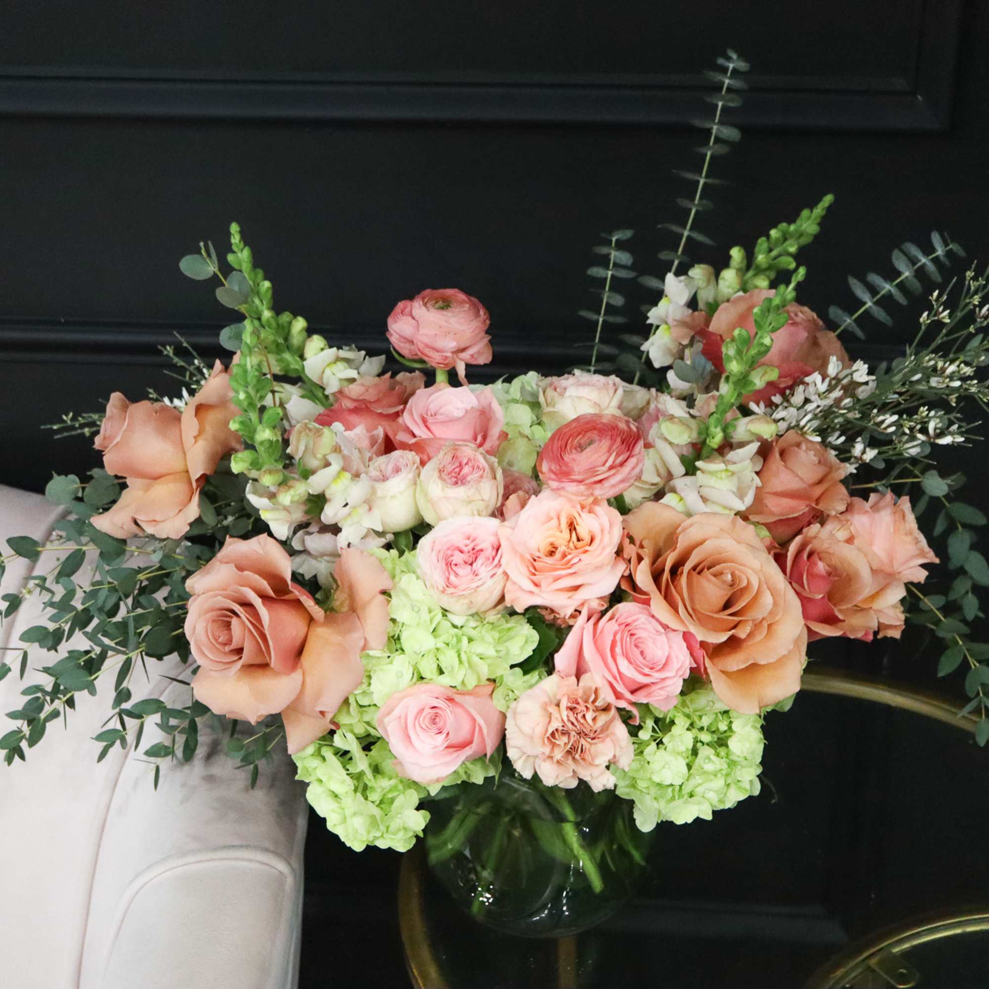 Peach and pink roses with green hydrangeas in a glass vase