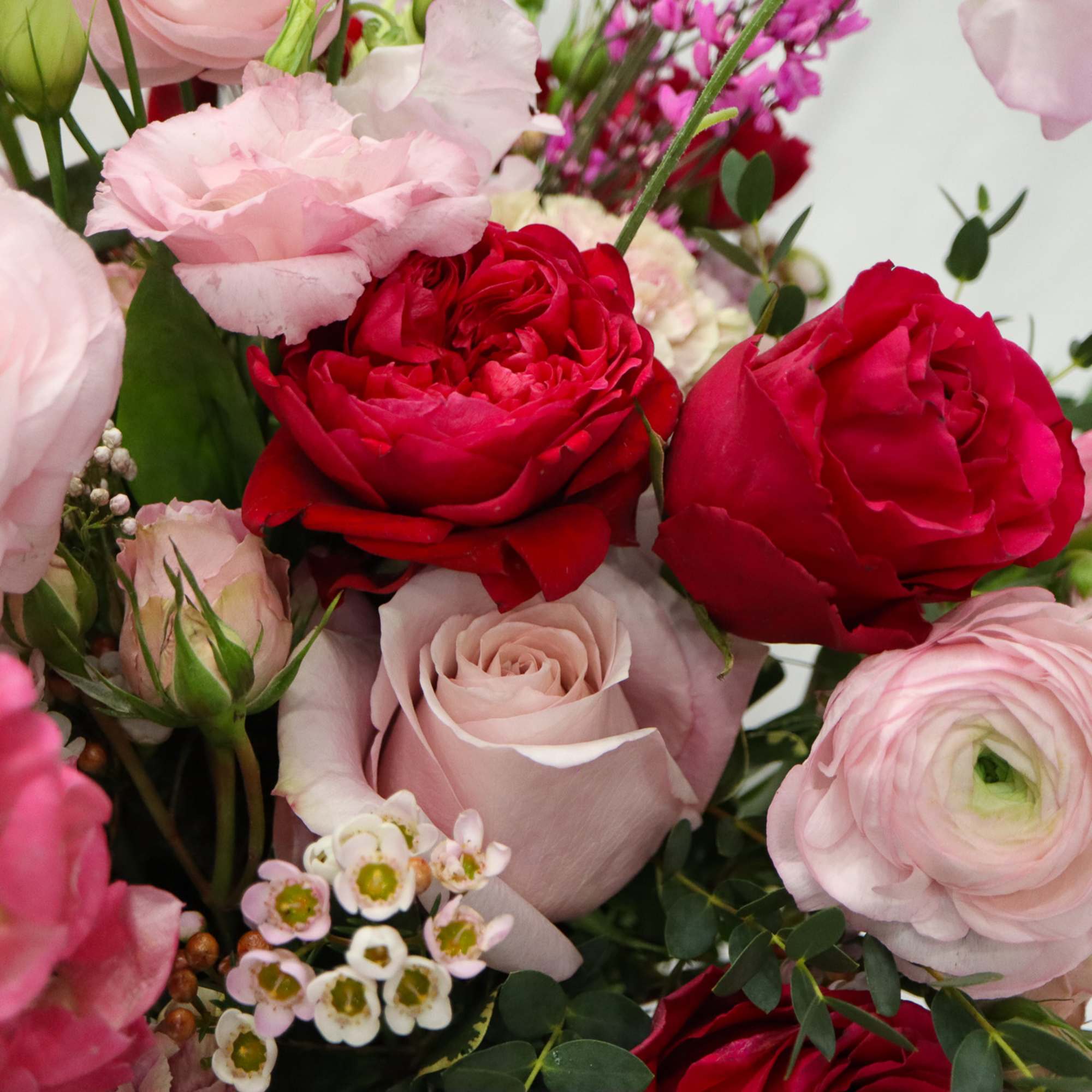 Bouquet of pink and red roses with pale ranunculus and small white blossoms