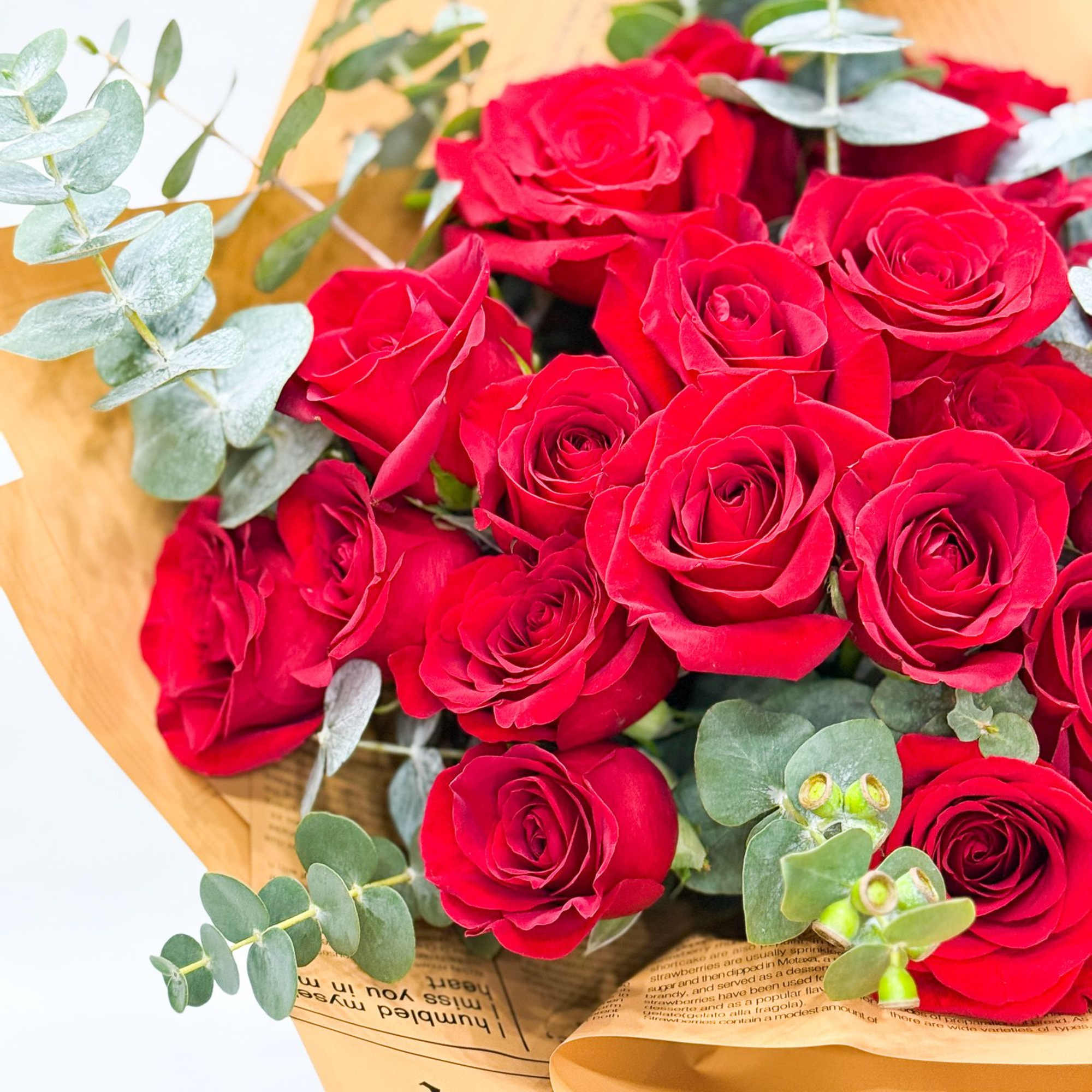 Bouquet of red roses with eucalyptus in tan paper wrap