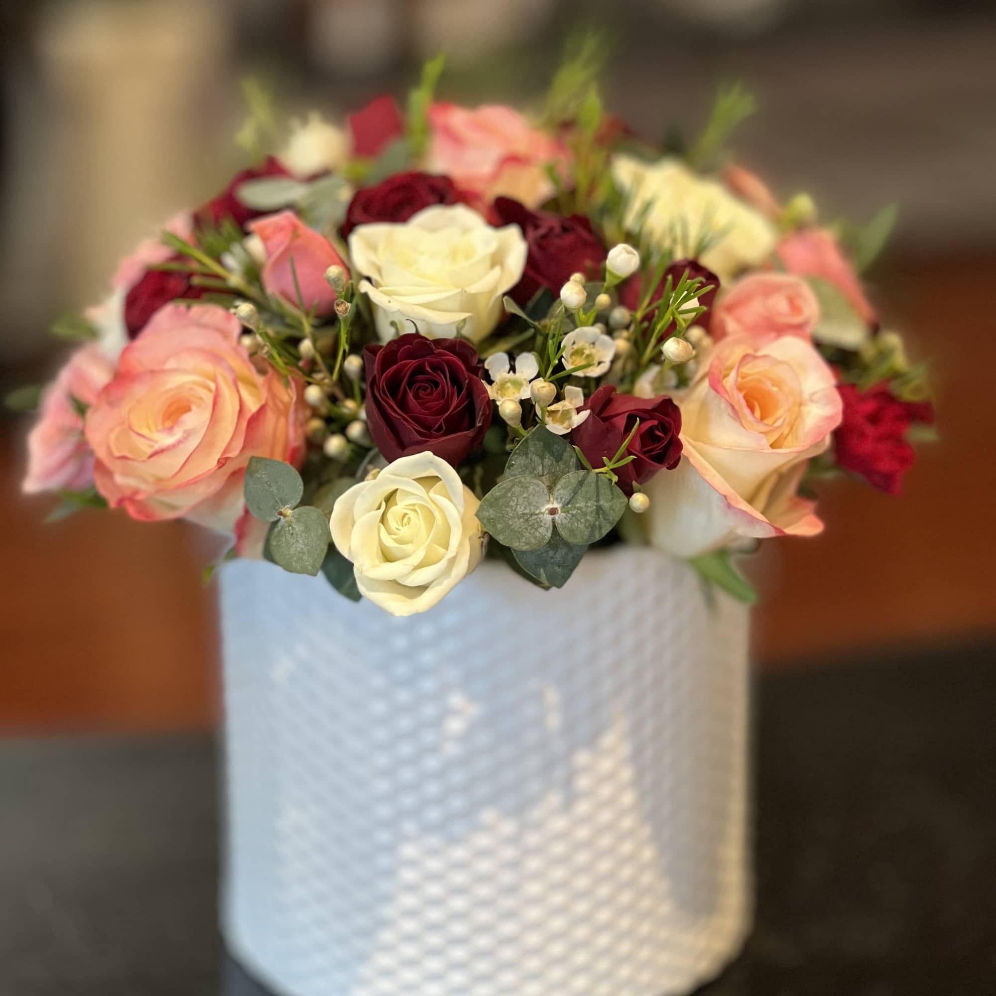 Bouquet of pink, cream, and burgundy roses in a white textured vase