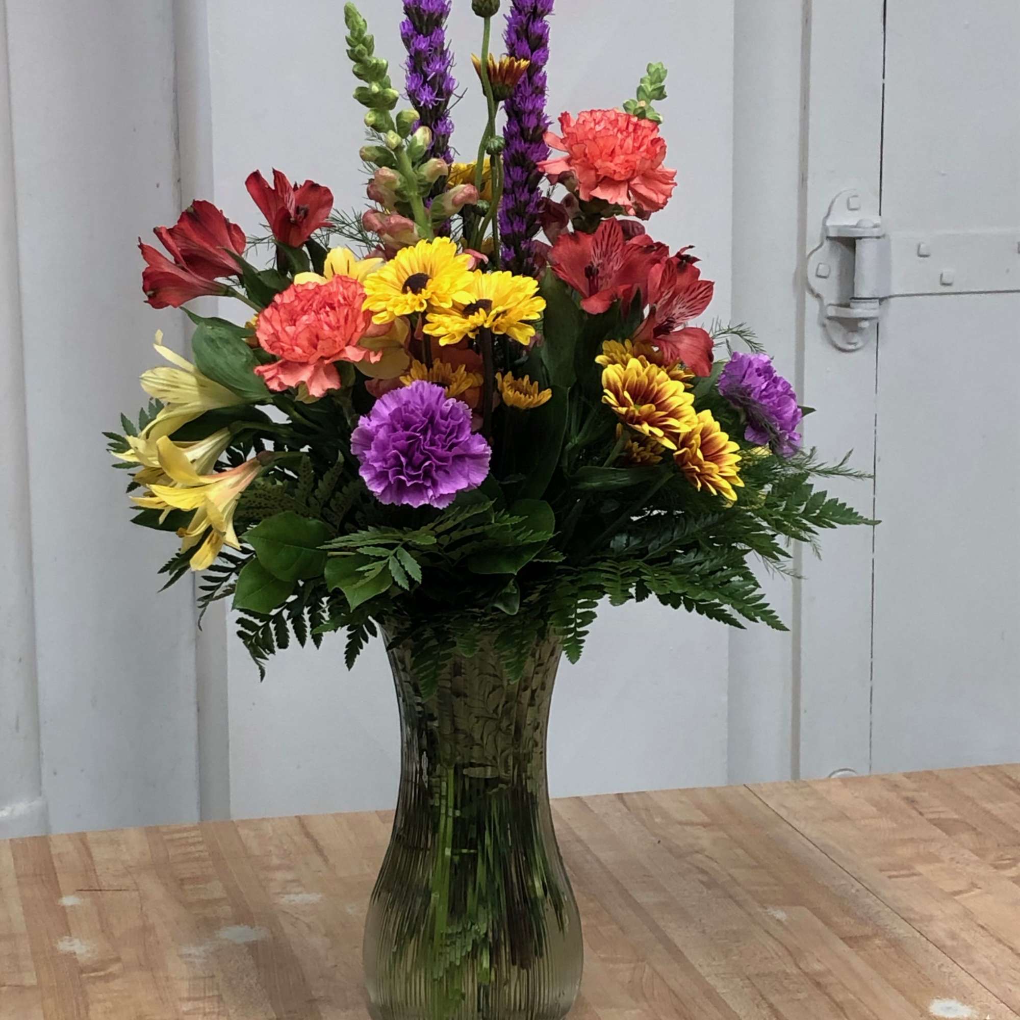 Colorful mixed flower arrangement in a tall glass vase