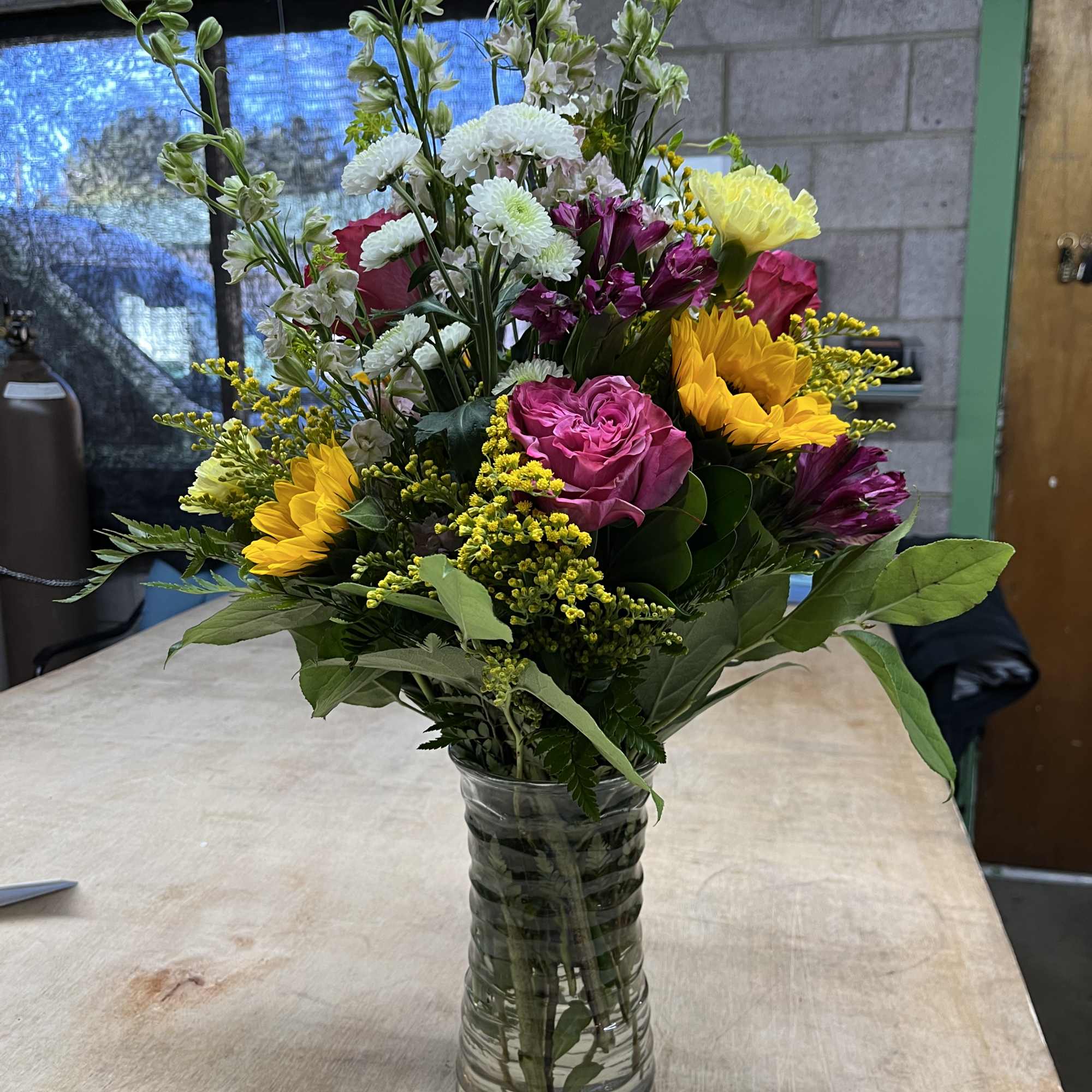Mixed bouquet in a clear glass vase with pink, yellow, white, and purple flowers