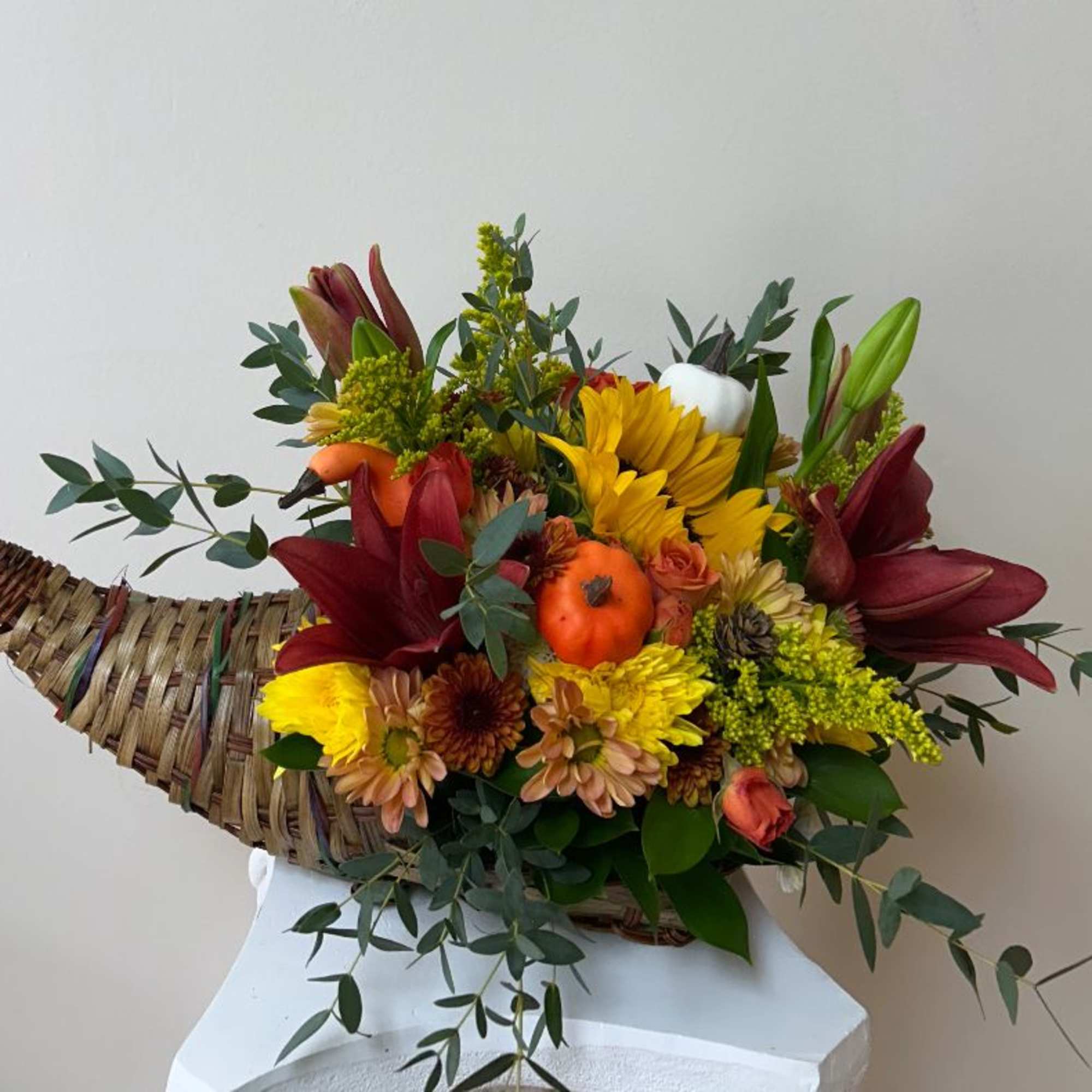 Autumn flower arrangement in a woven cornucopia basket with sunflowers and lilies
