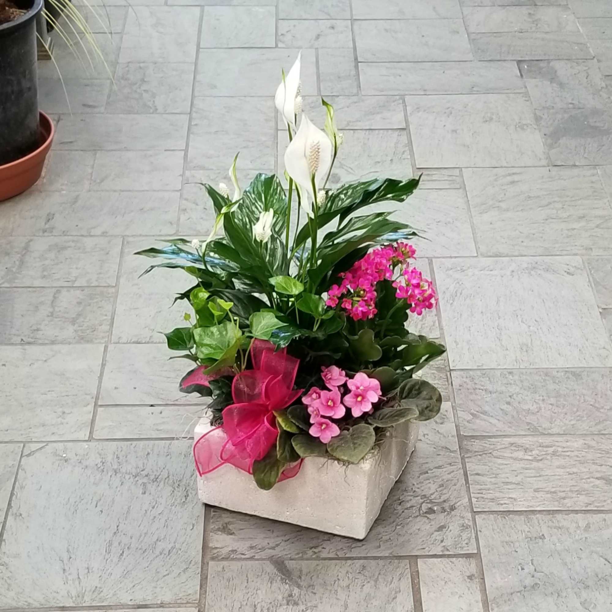 Potted arrangement with white peace lilies and pink flowers in a square container