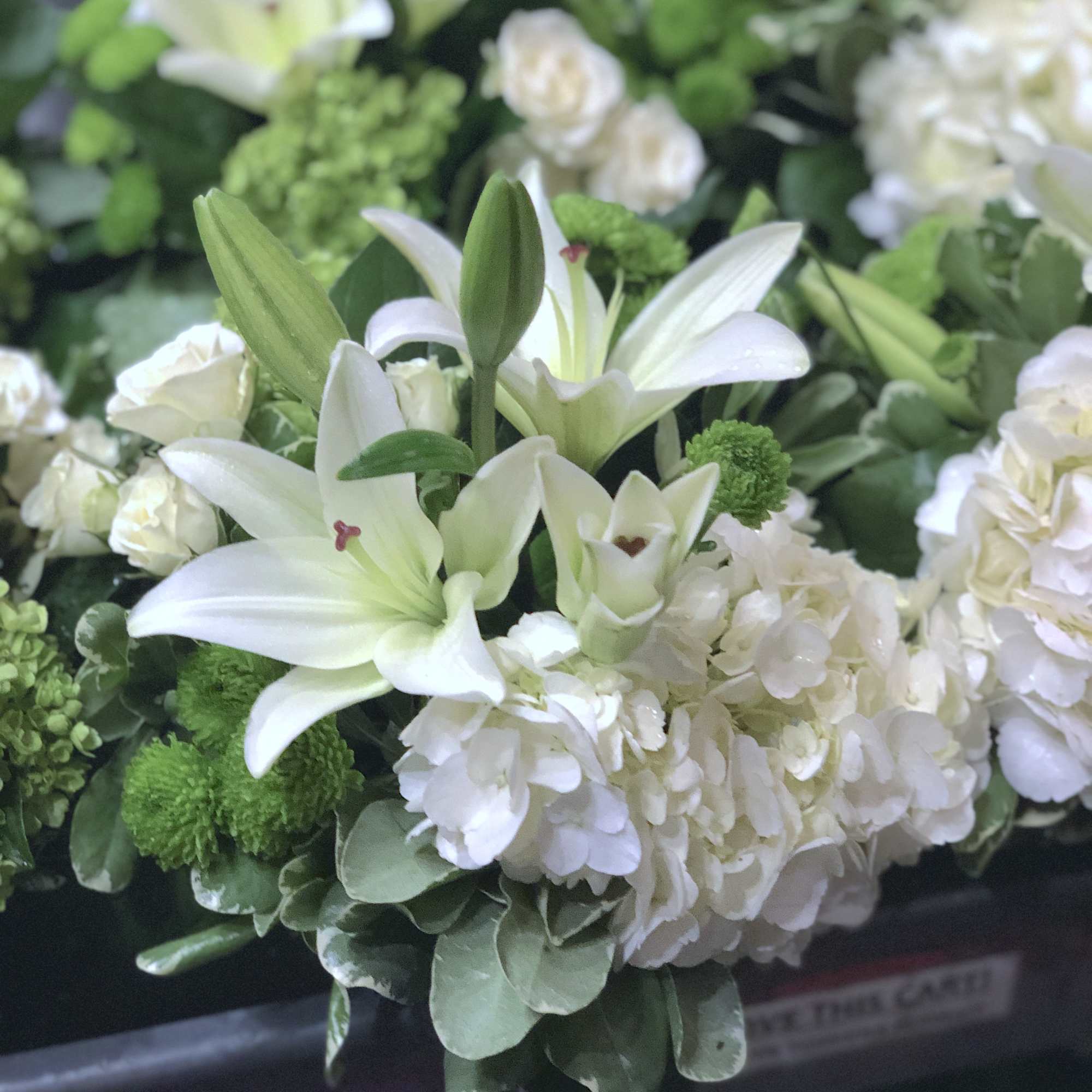White lilies and hydrangeas with green accents in a bouquet