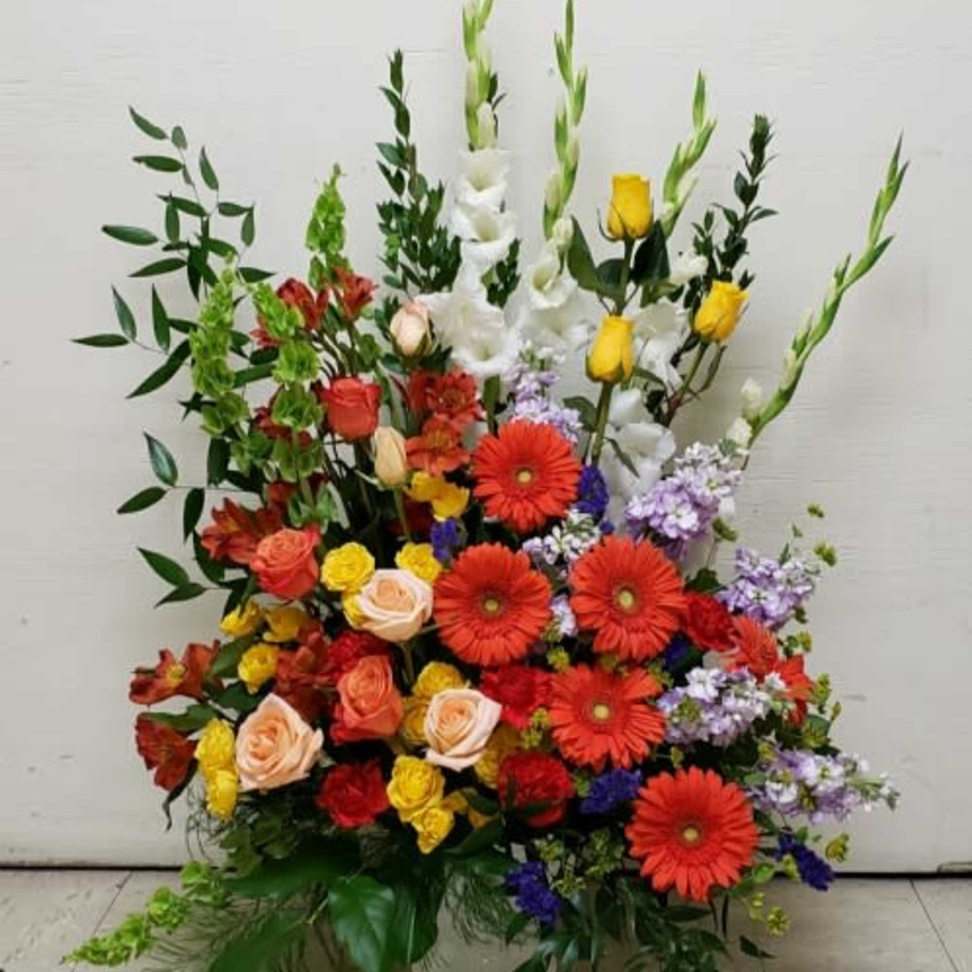 Large mixed flower arrangement with red gerberas, roses, and white gladiolus