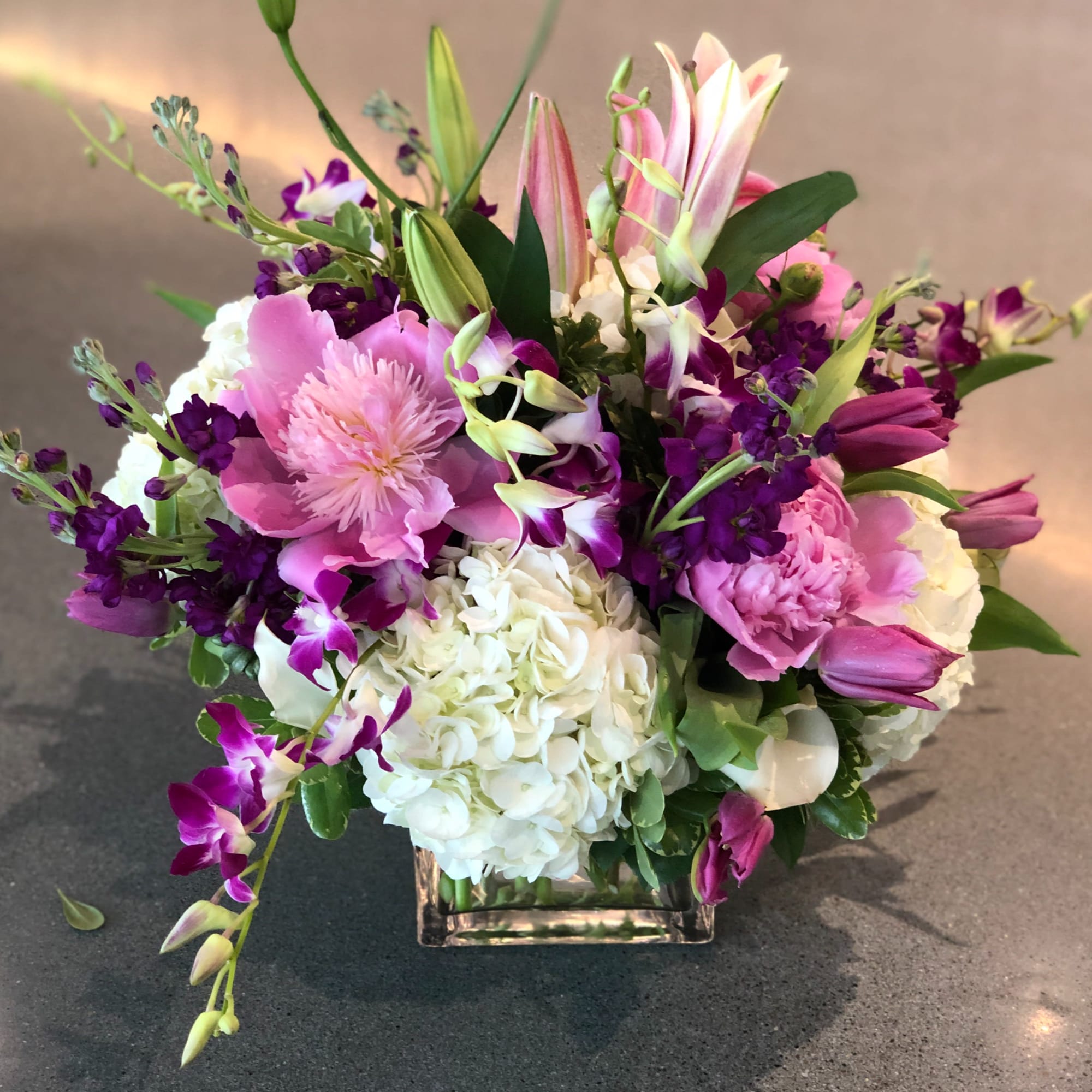 Pink and white mixed flower arrangement in a square glass vase