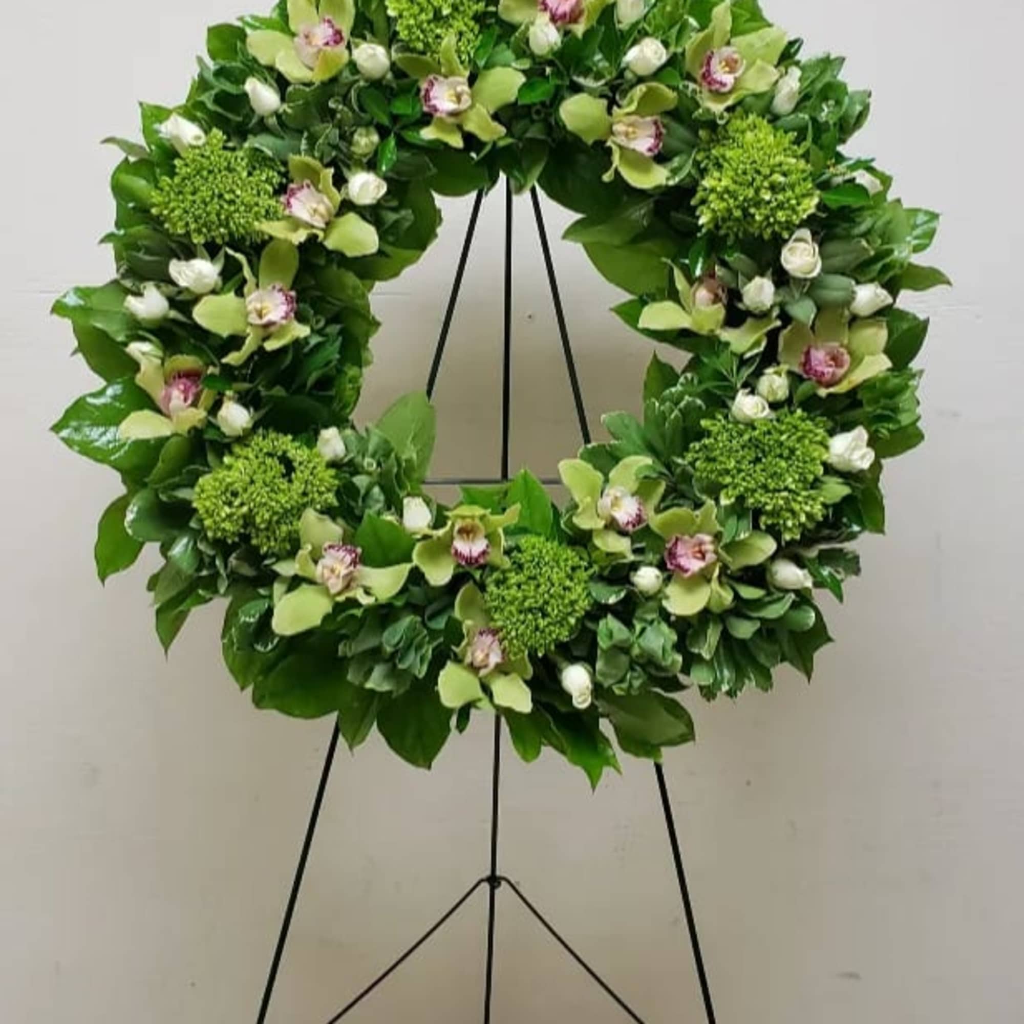 Standing green and white floral wreath with orchids and roses on a metal easel