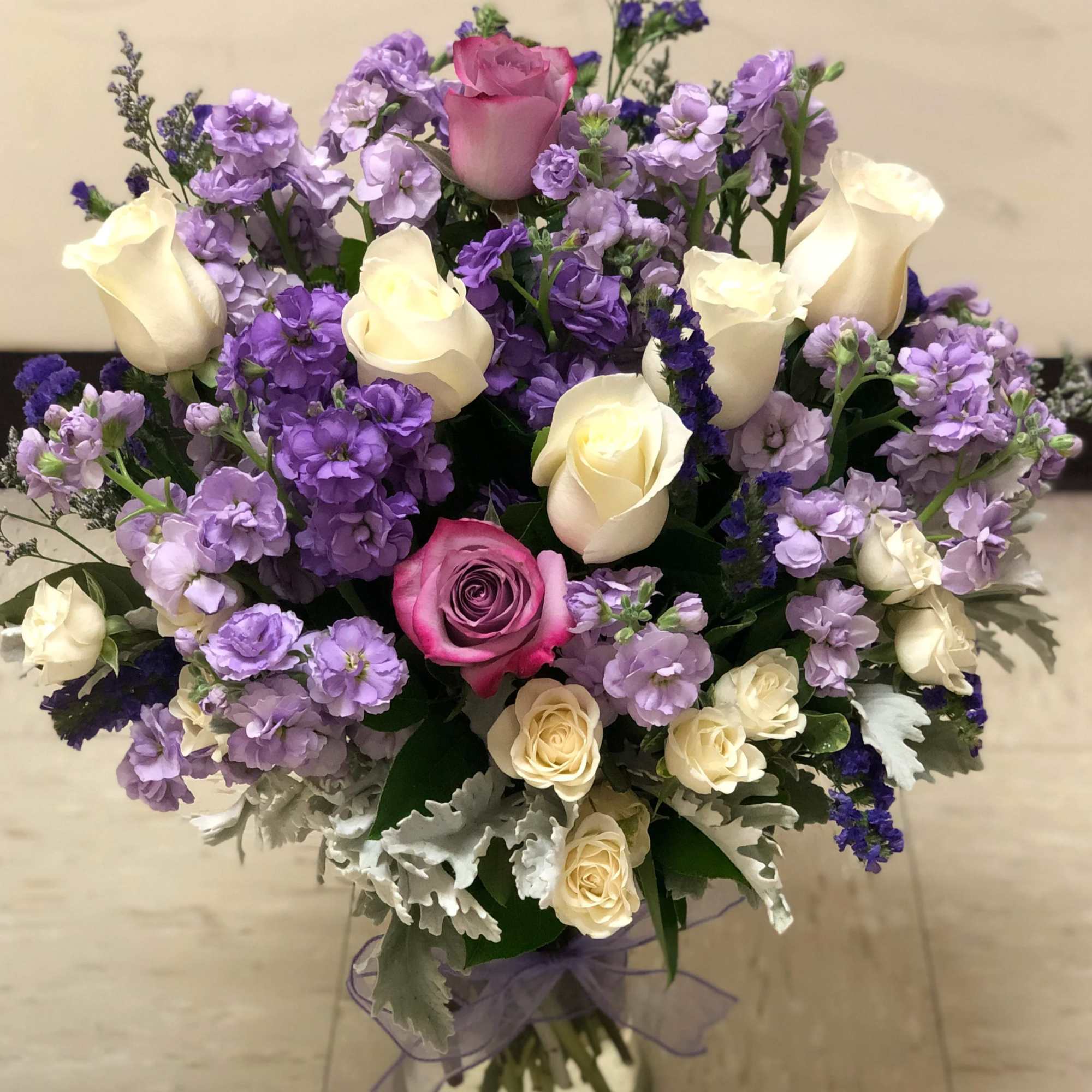 Bouquet of pink and cream roses with purple flowers in a glass vase